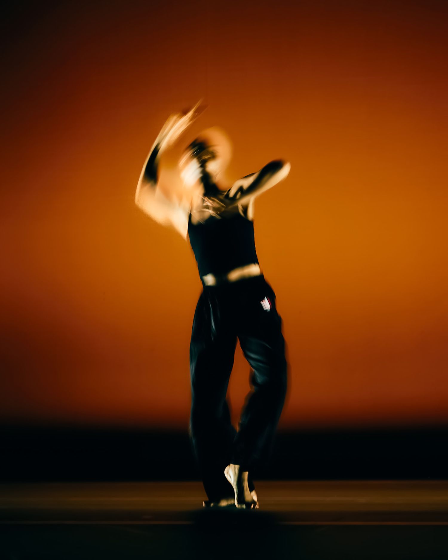 Dancing figures in silhouette against warm orange sky at sunset.