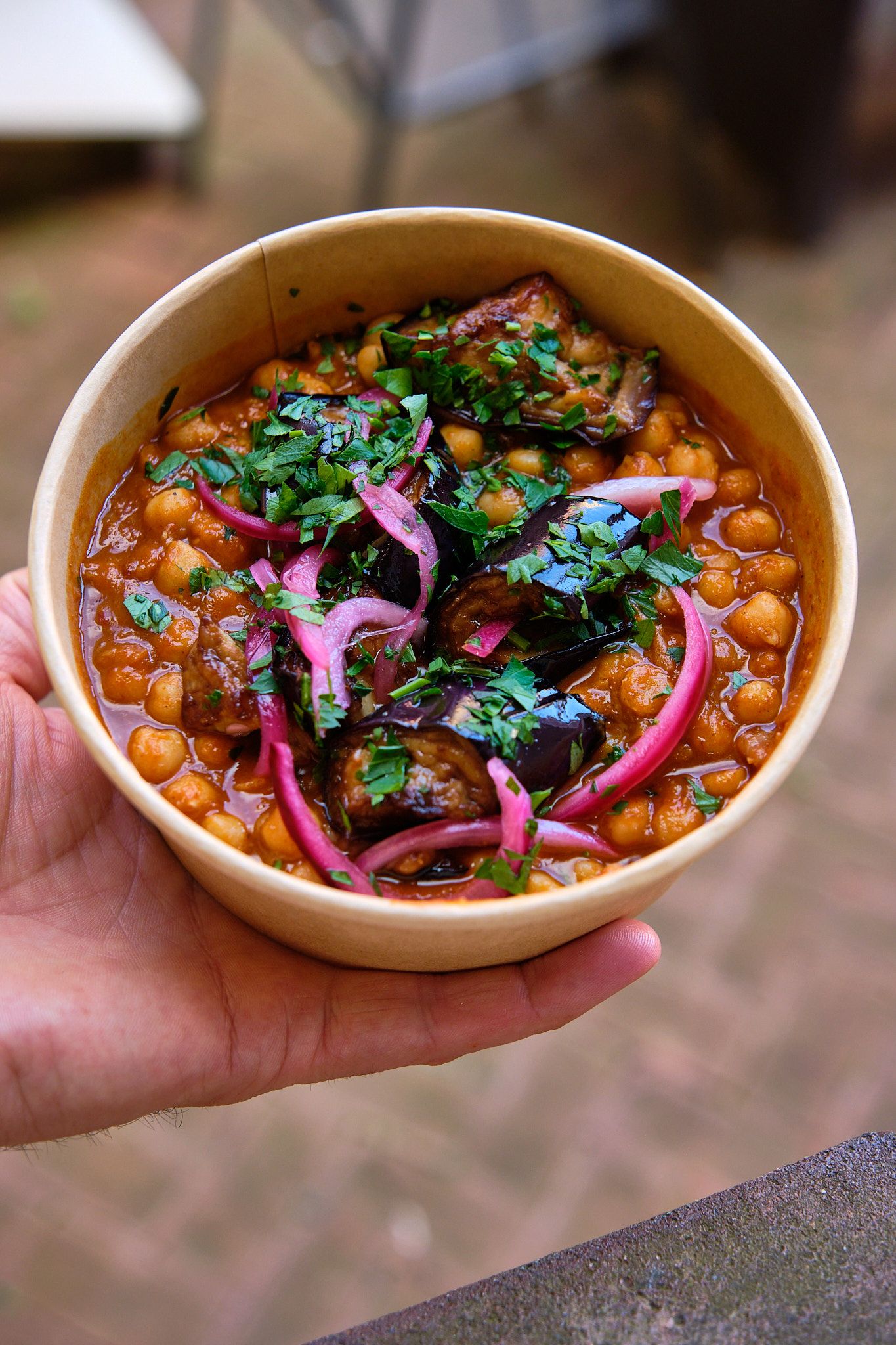 Chickpea stew garnished with purple onions and fresh cilantro served in ceramic bowl.