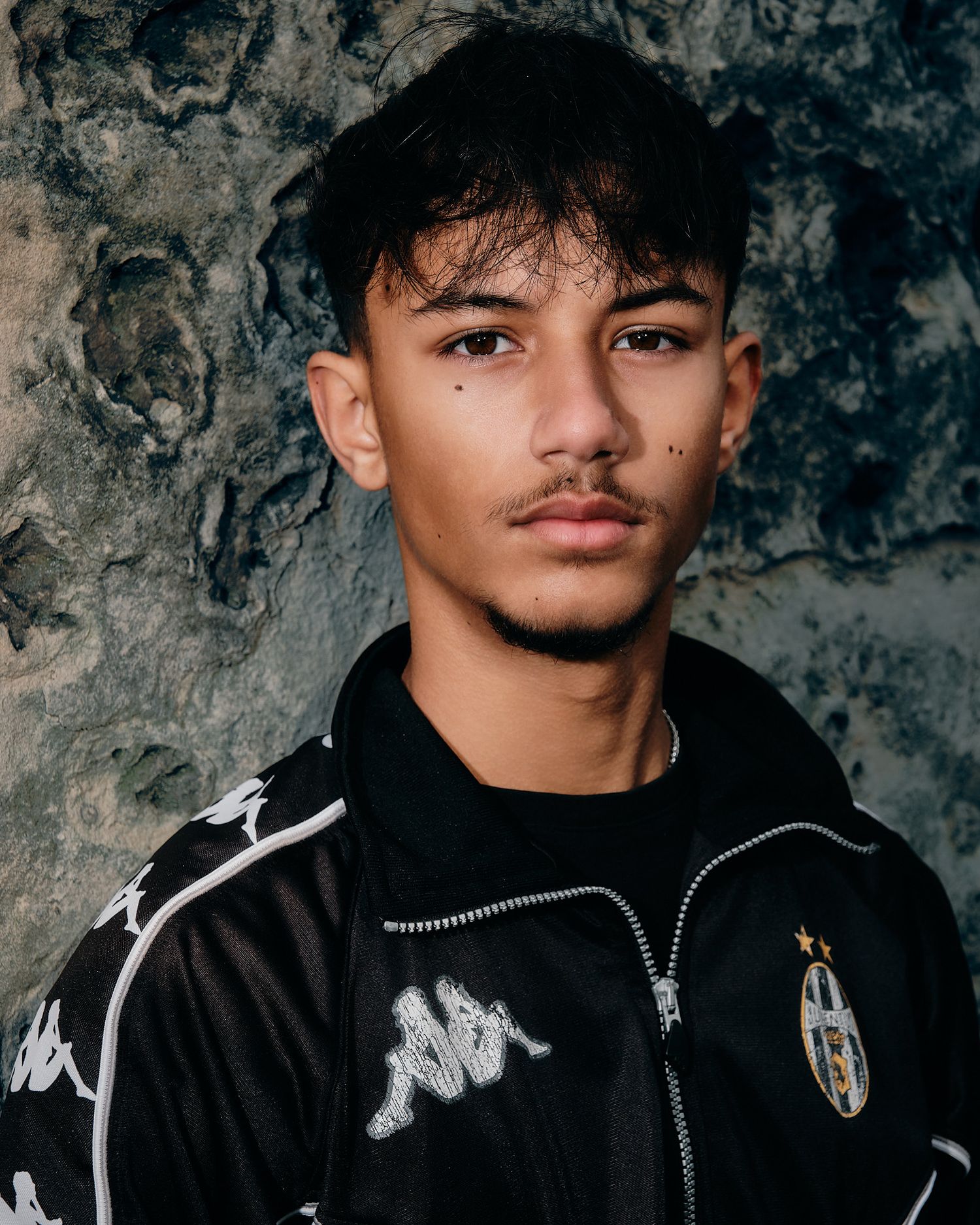 Close-up fashion shot of black Kappa Juventus jacket with white logo details.
