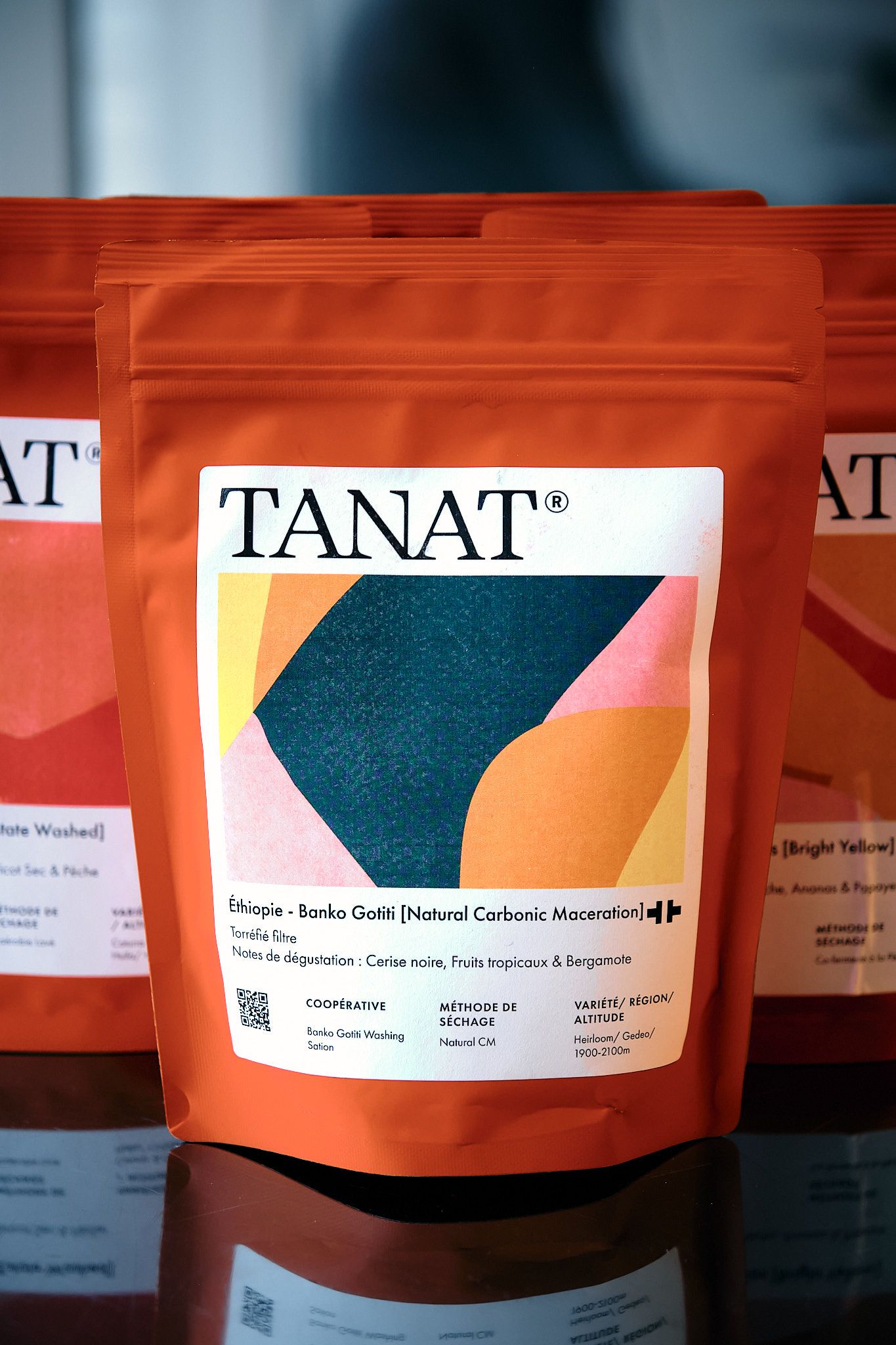 Close-up of TANAT coffee bag featuring bold geometric artwork in teal and orange colors.