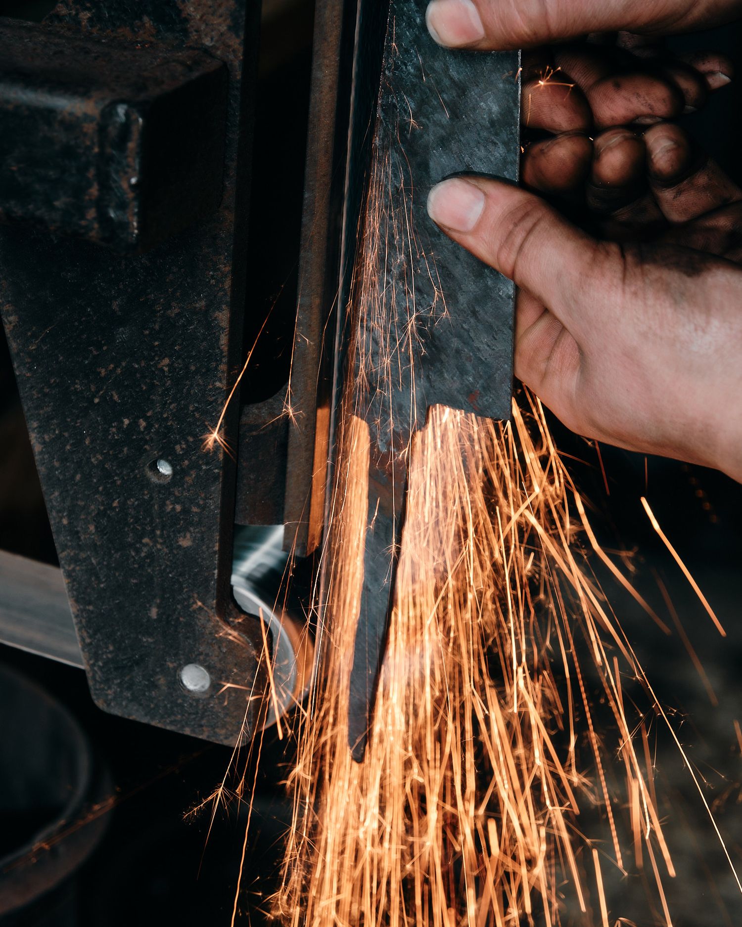 Close-up of metalworking with orange sparks flying during grinding process.