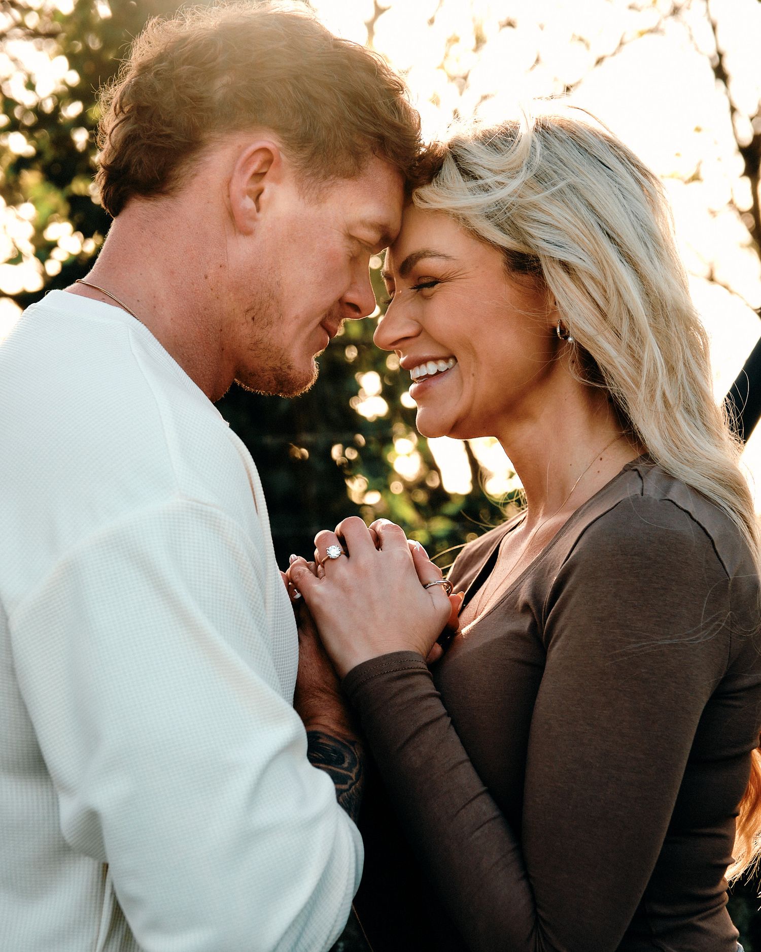 Candid romantic moment between couple in outdoor setting during golden hour.