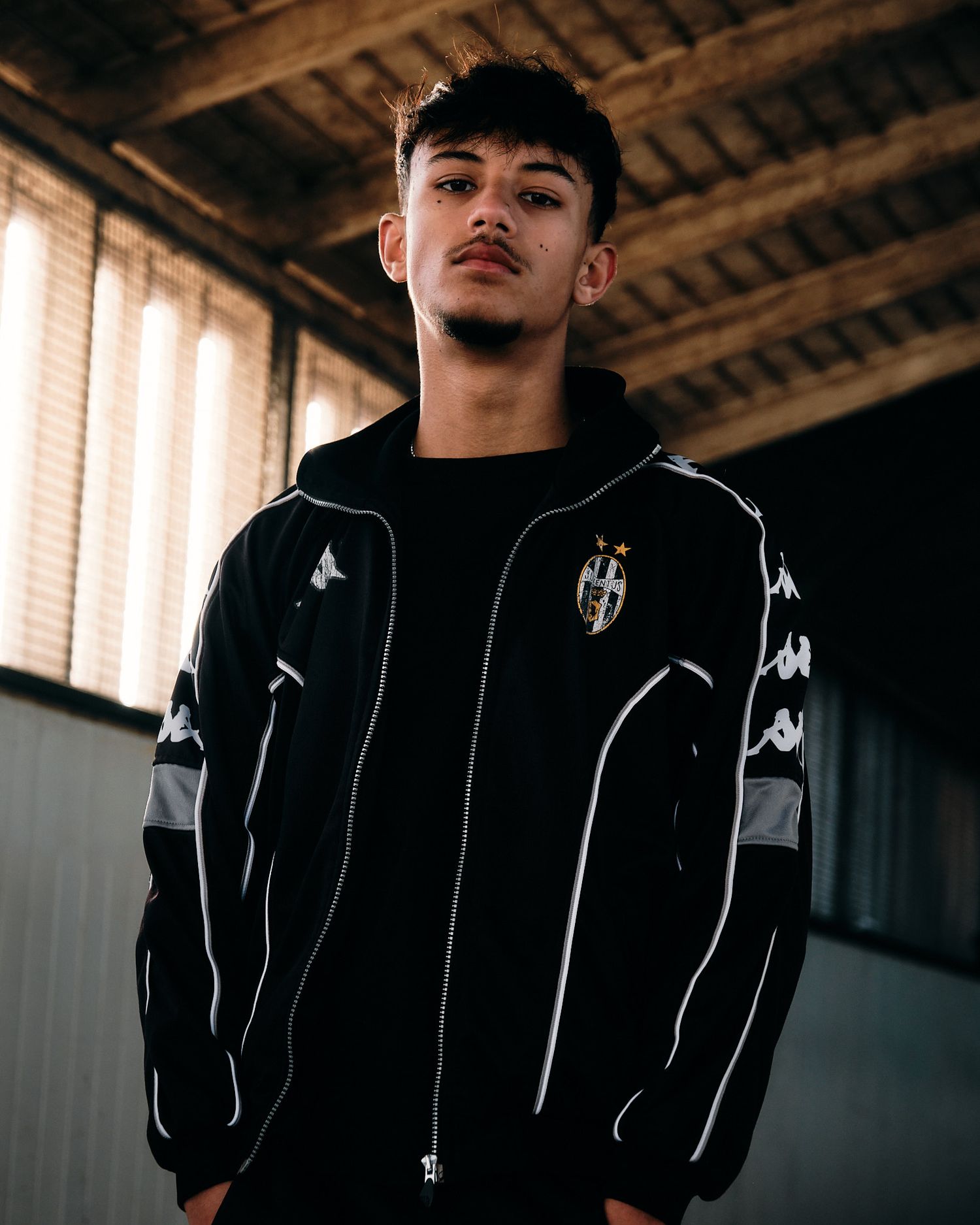 Model showcasing black Juventus athletic jacket with distinctive Kappa branding.