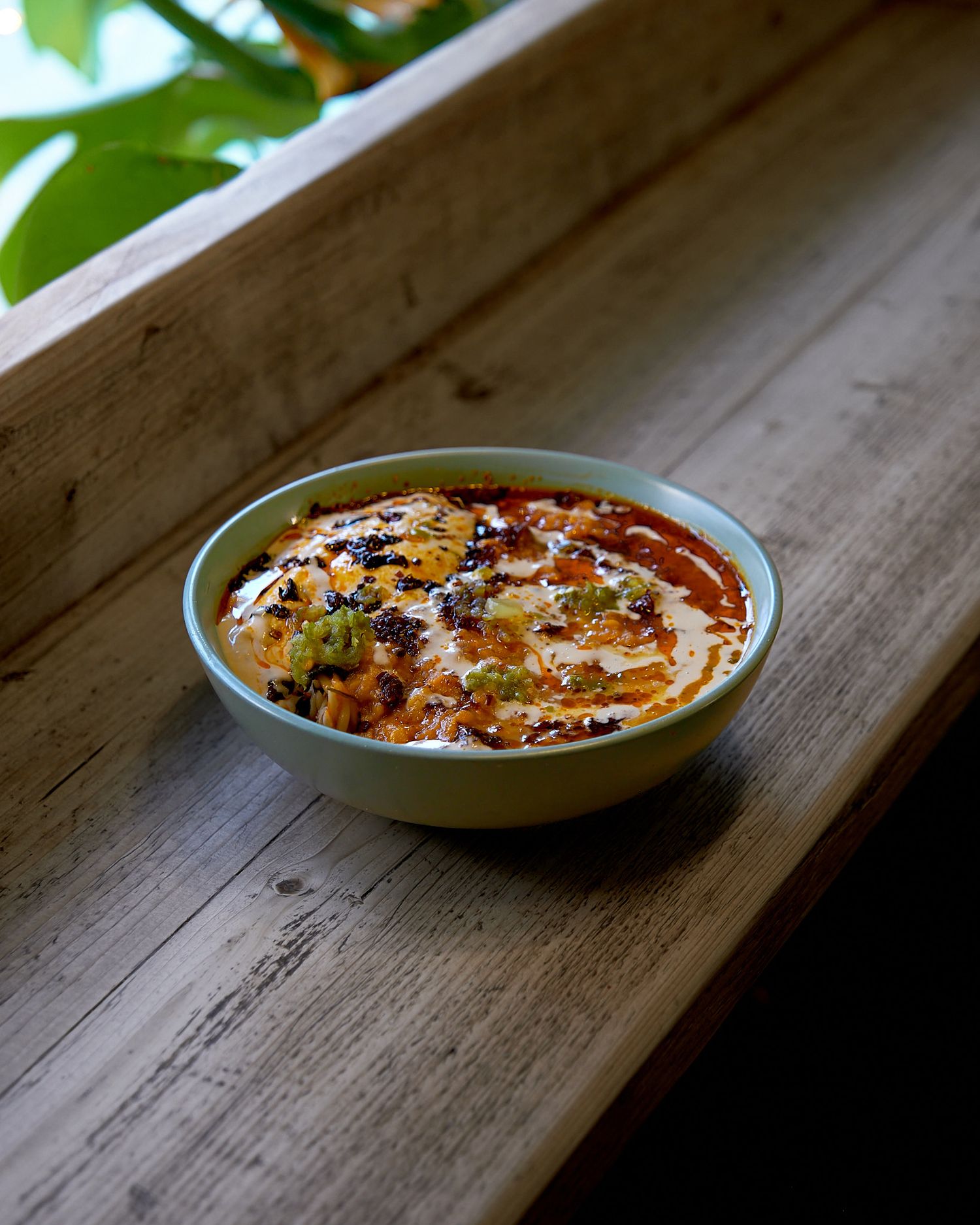 Light blue dish with creamy baked dip on wooden surface with natural lighting.