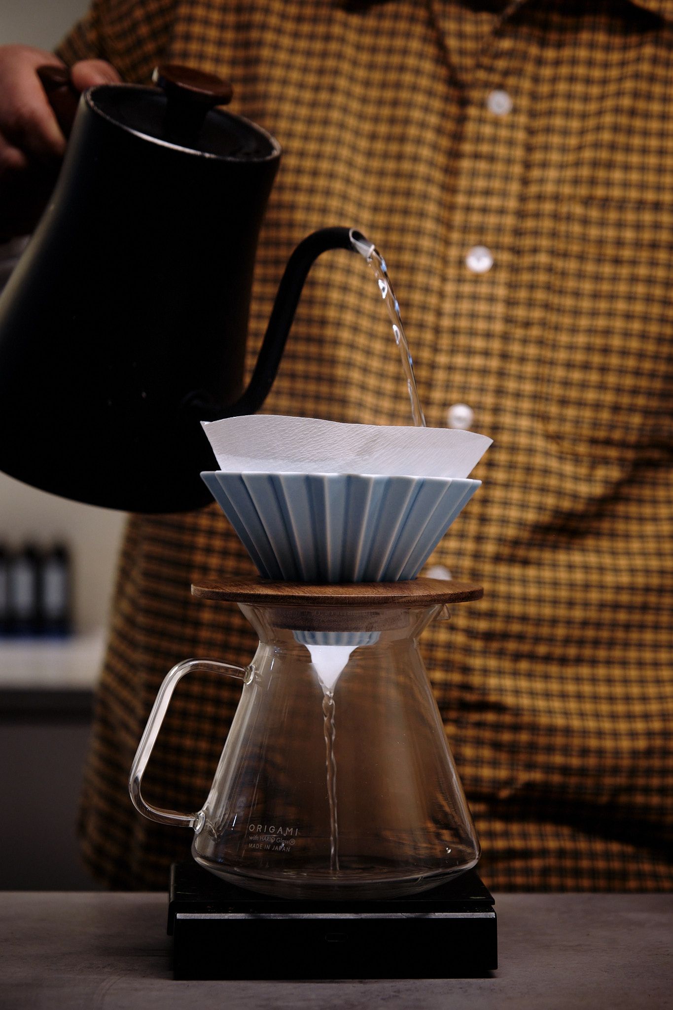 Water being poured into a Hario V60 coffee dripper with blue filter paper for brewing.