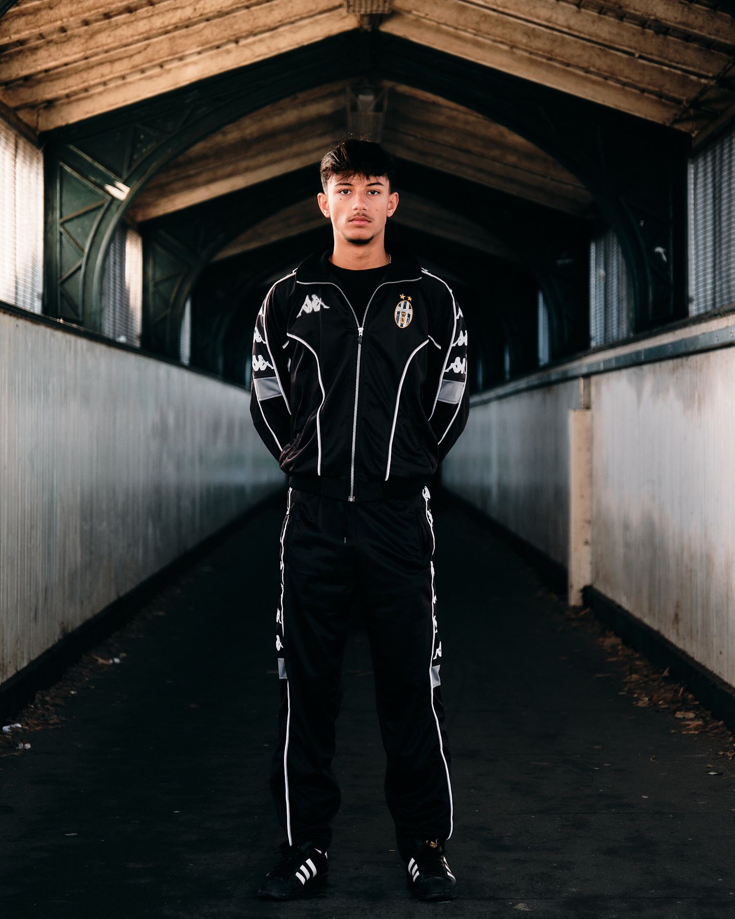 Dramatic portrait in dark tunnel wearing black and white Kappa athletic wear.