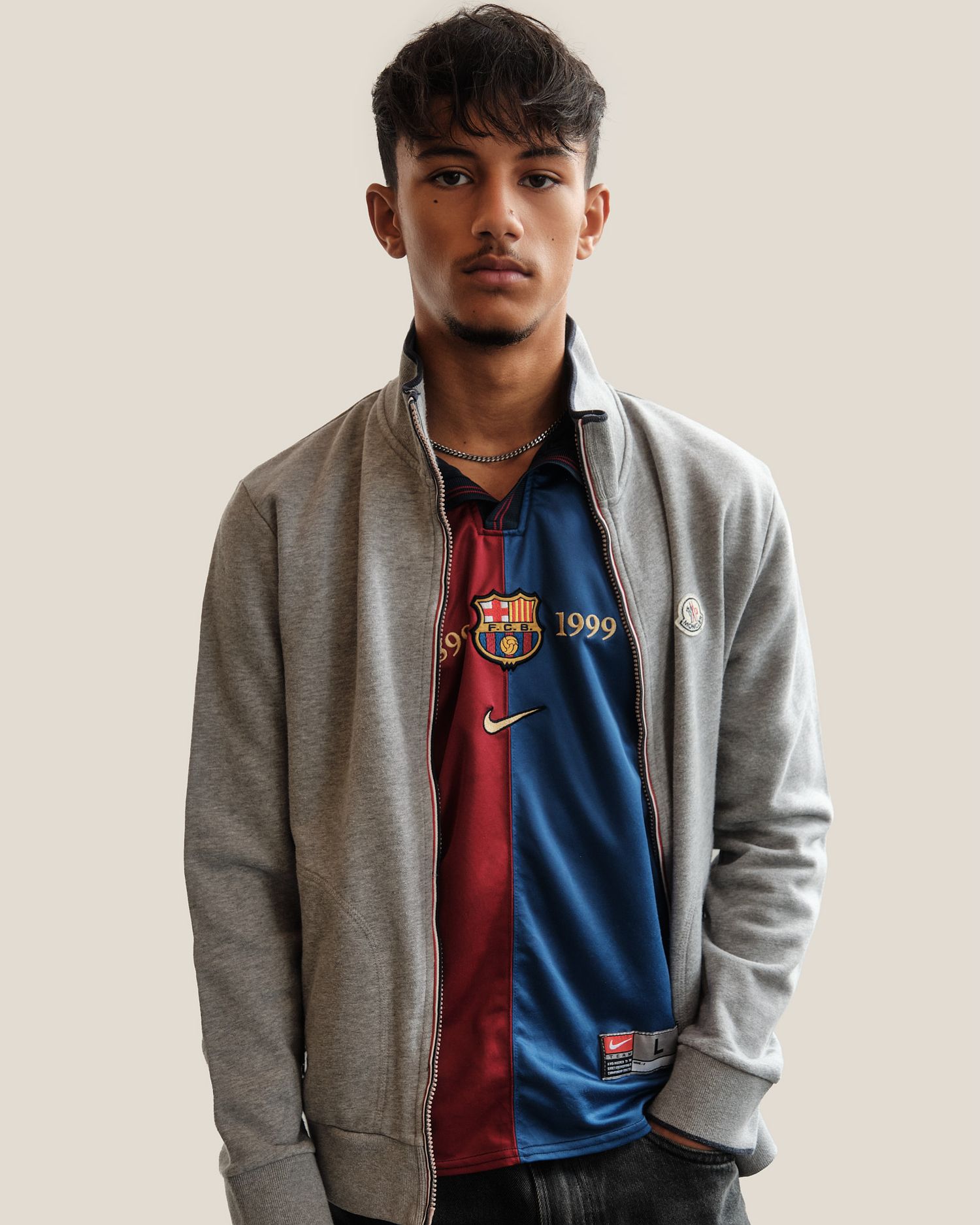 Grey bomber jacket styled with retro sports jersey against neutral background.