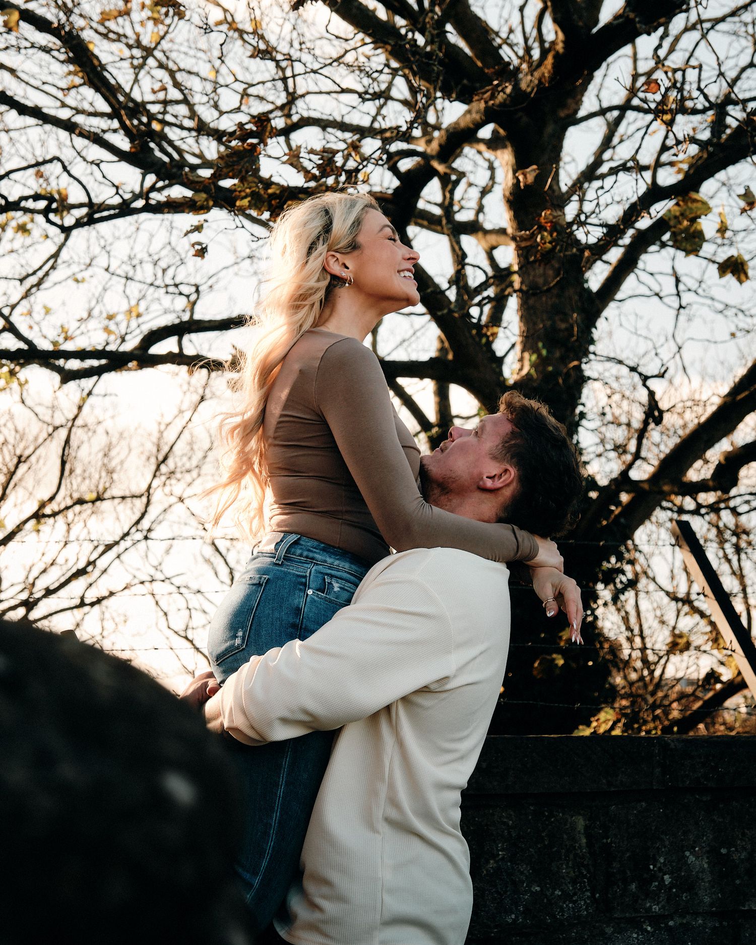 Intimate couple portraits against a bare tree during sunset.
