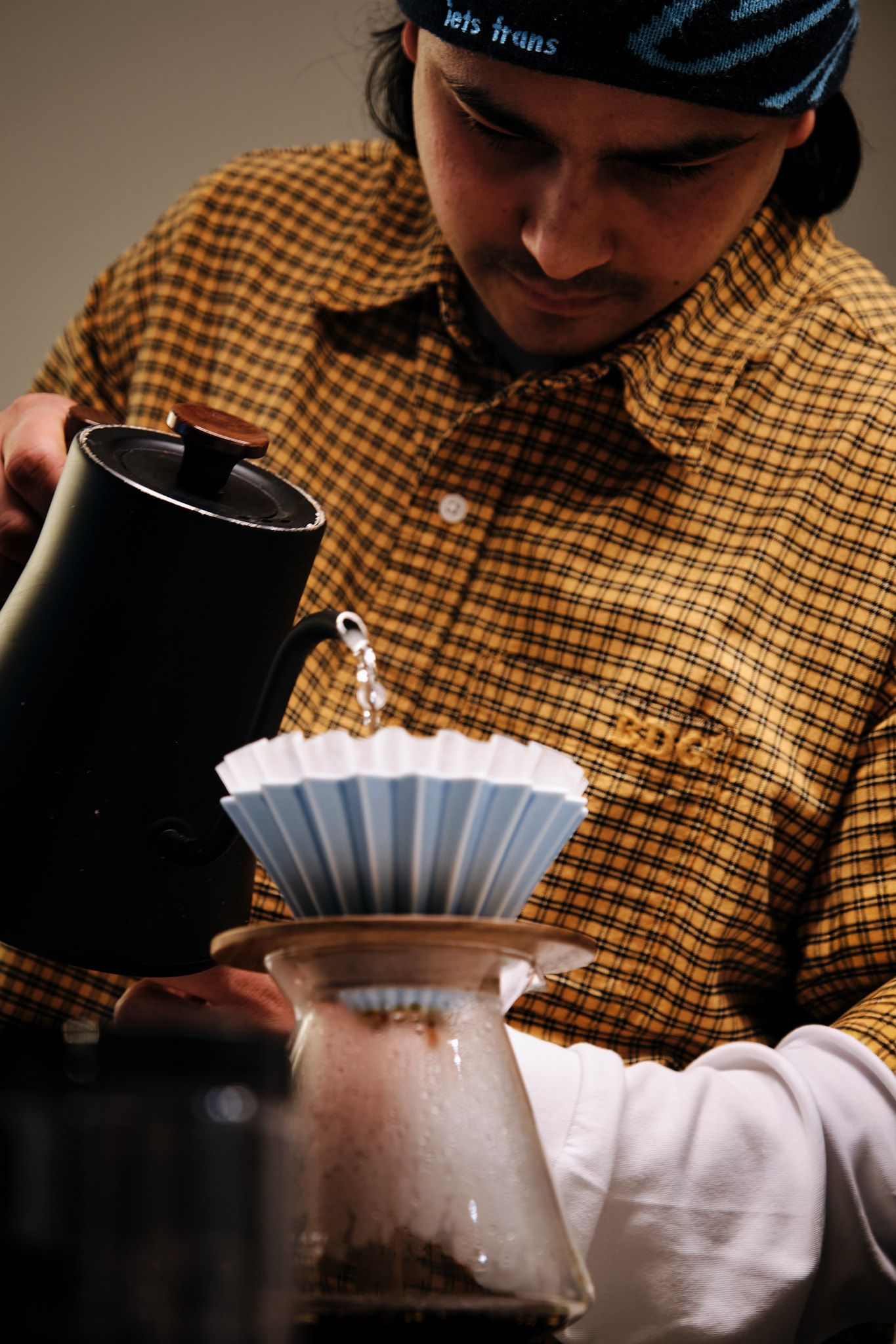 Pour-over coffee being prepared with a black kettle and white filter.