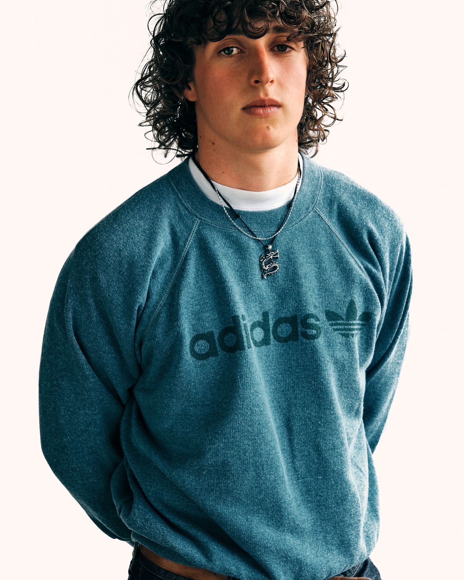 Person wearing vintage blue Adidas sweatshirt against white background.