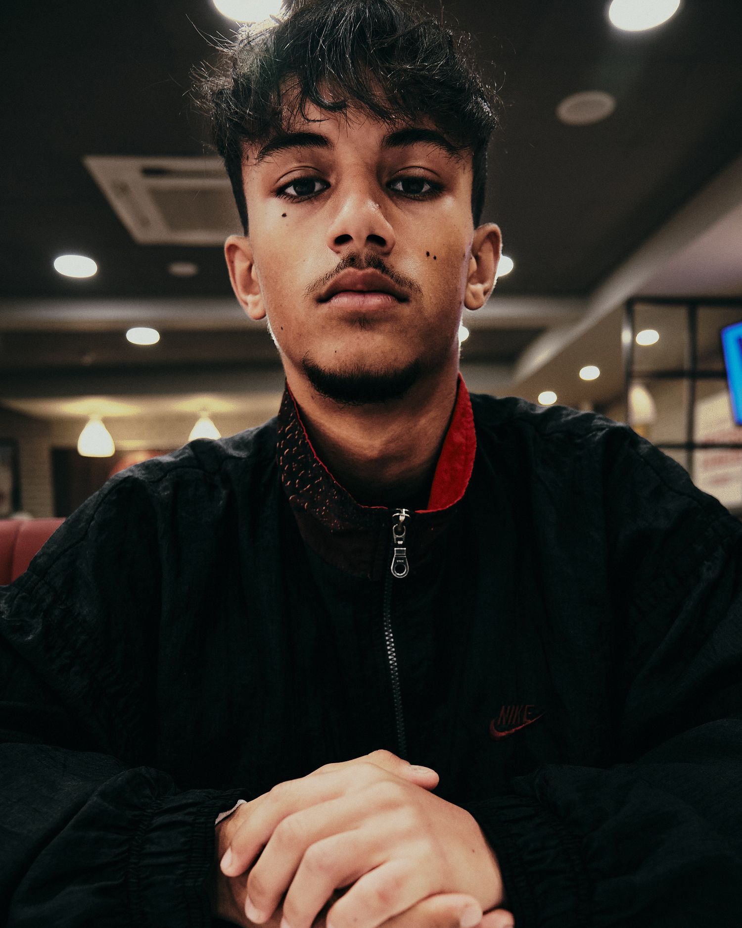 Indoor portrait showing casual black athletic wear under moody lighting.