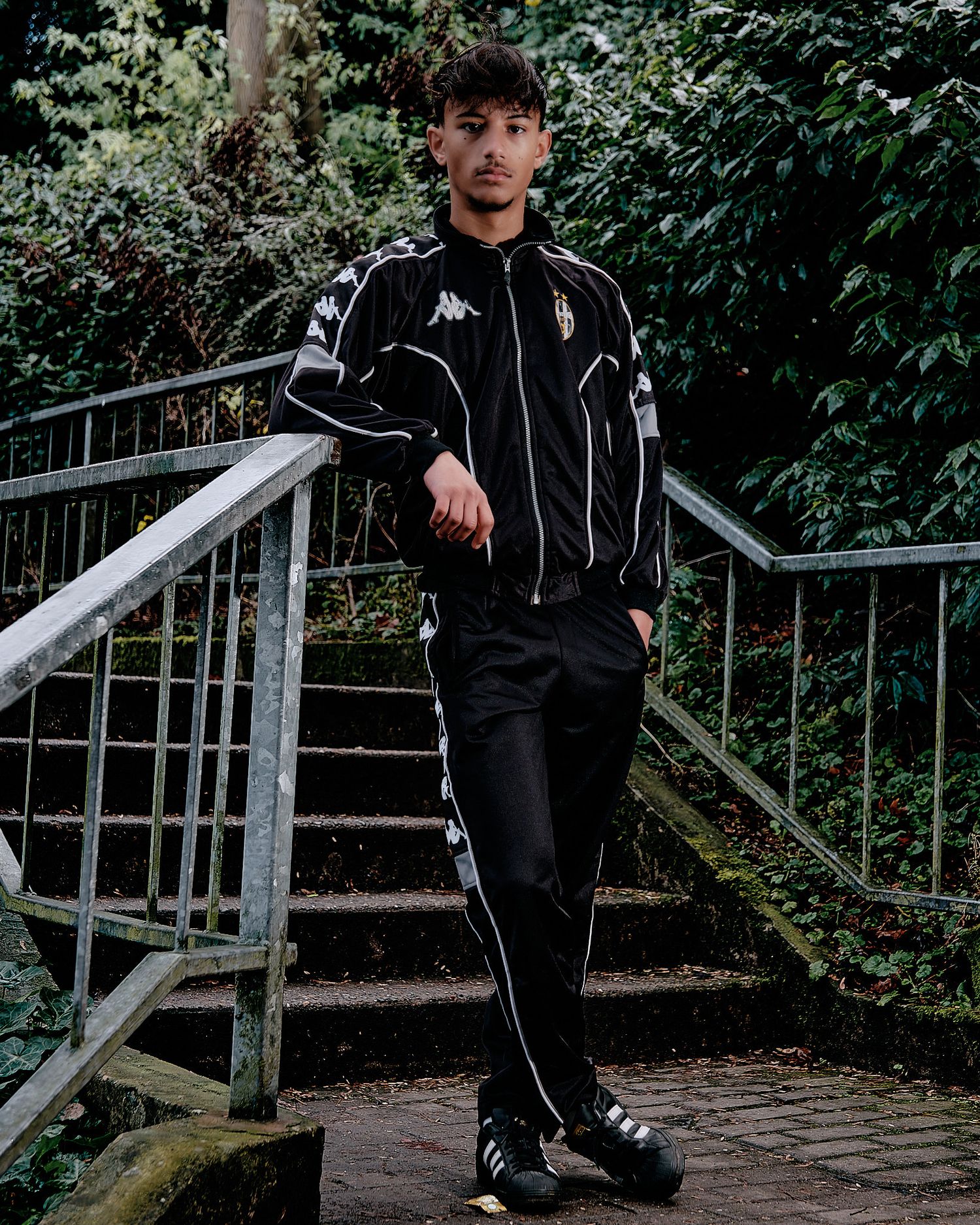 Athletic wear fashion shoot on outdoor steps with greenery and railing.