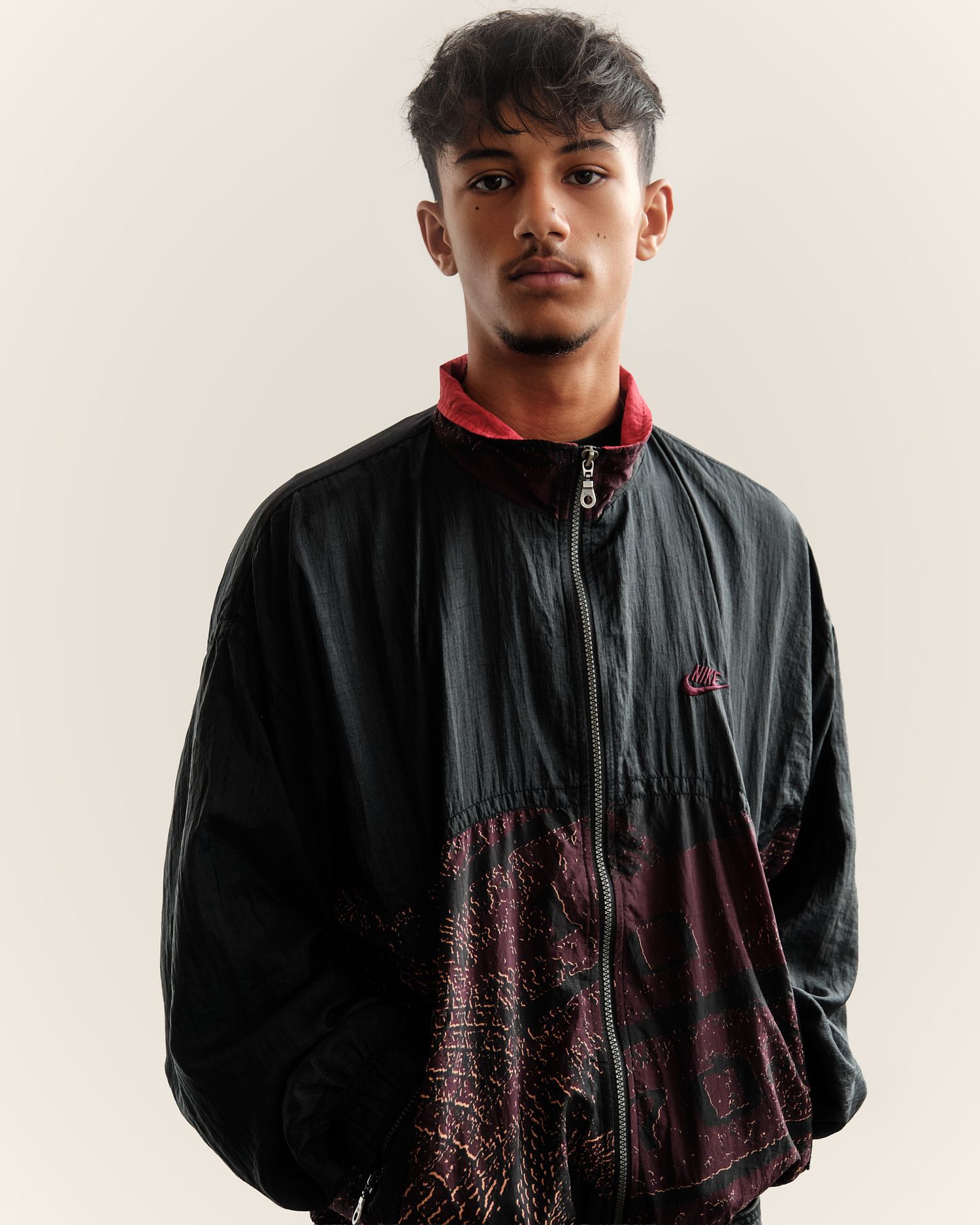 Black windbreaker jacket with subtle pattern detail photographed in studio.