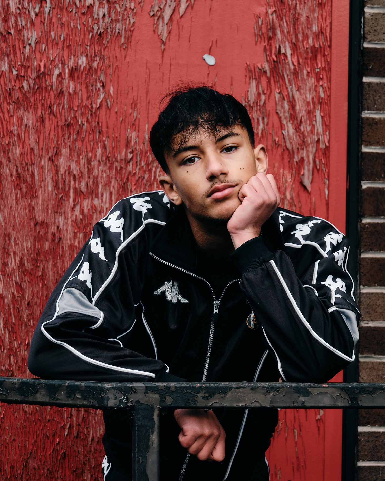 Stylish athletic wear photo featuring Kappa jacket against distressed red background.