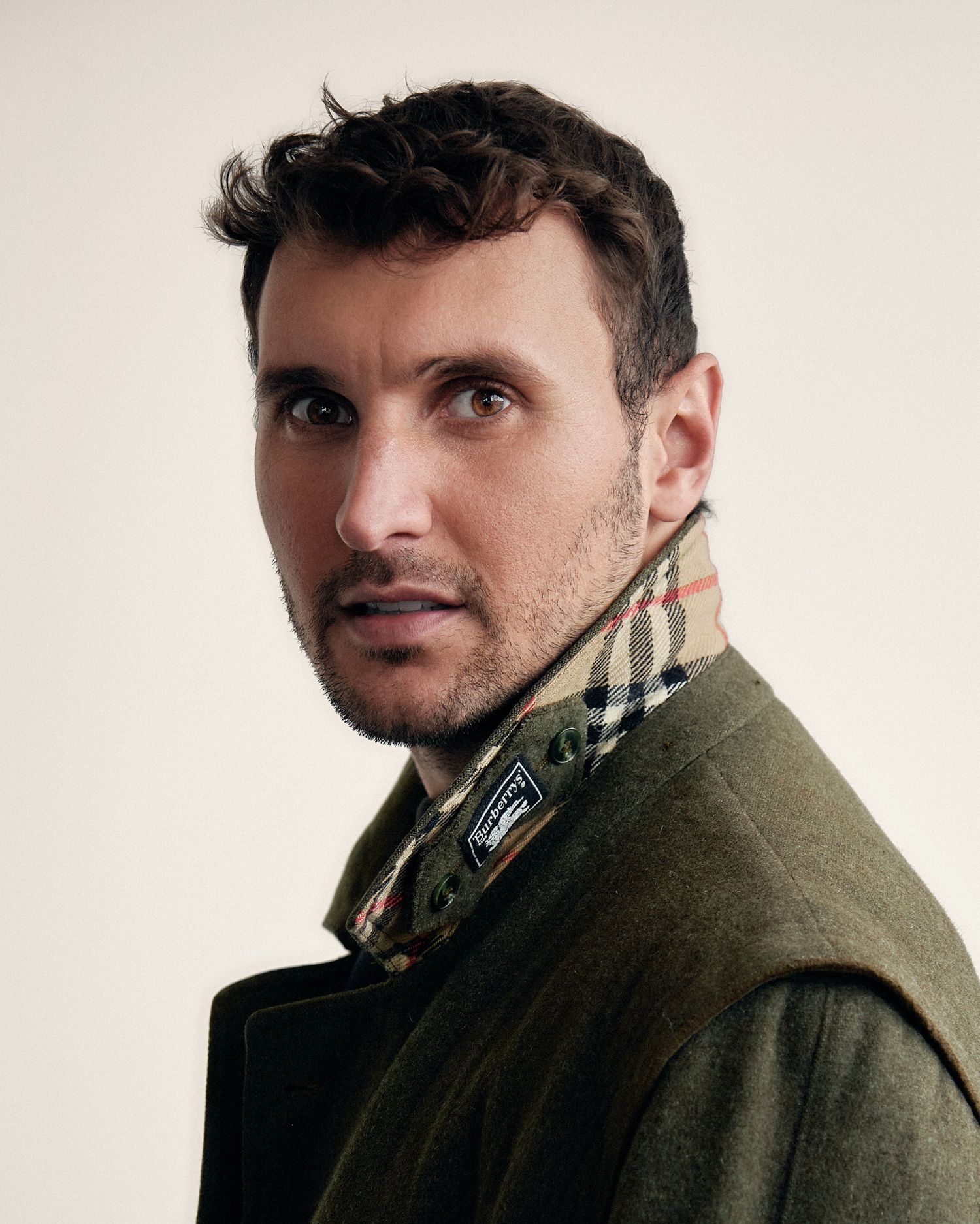 Portrait shots of person in olive coat against white background.