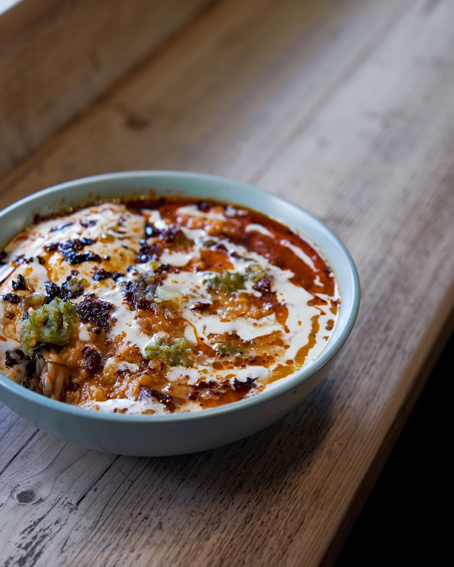Close-up view of a baked dip in a light blue ceramic dish on a rustic wooden table.