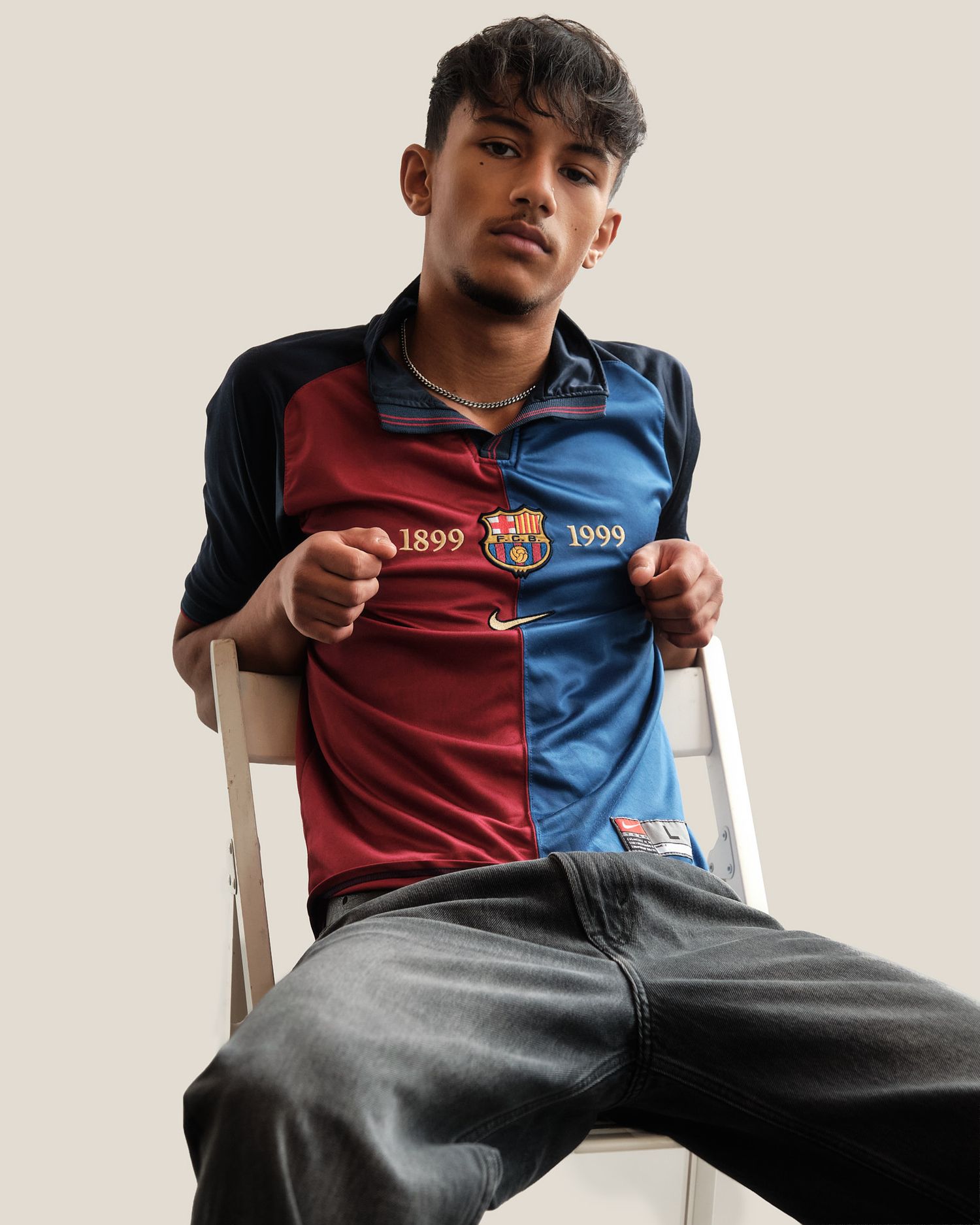 Model seated displaying vintage Barcelona FC jersey from 1899-1999 commemorative collection.