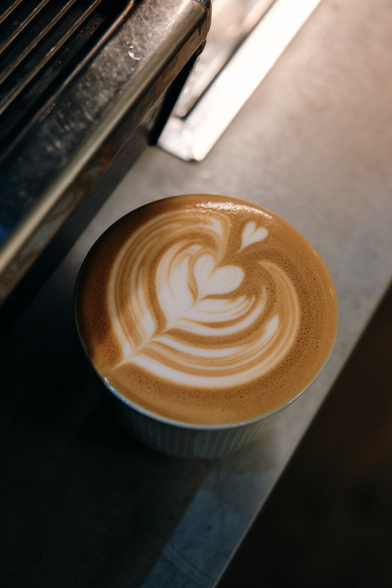 Latte art showing a white heart design in golden brown coffee foam.