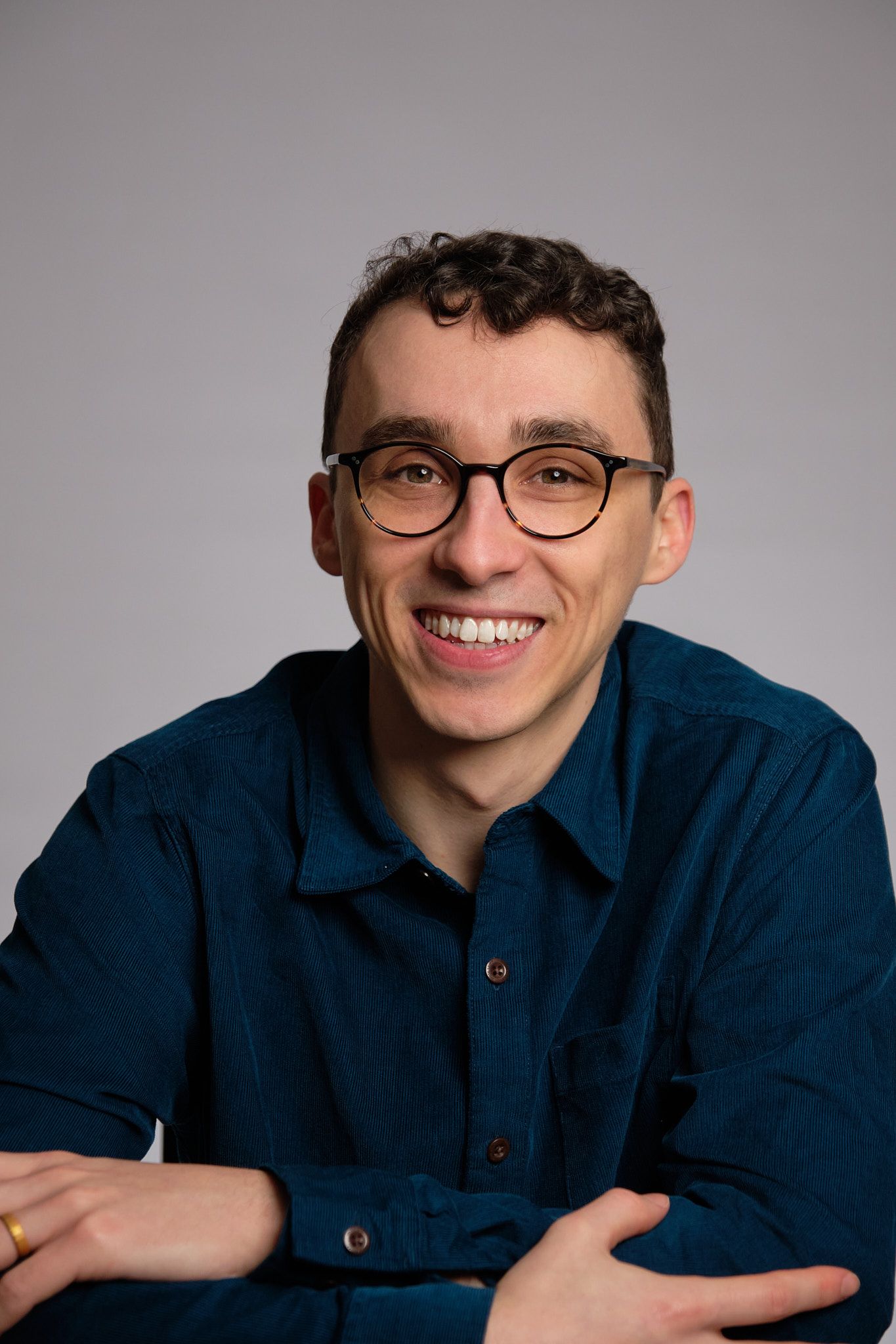 Professional headshot series showing expressions and poses in a navy blue shirt against a light gray background.