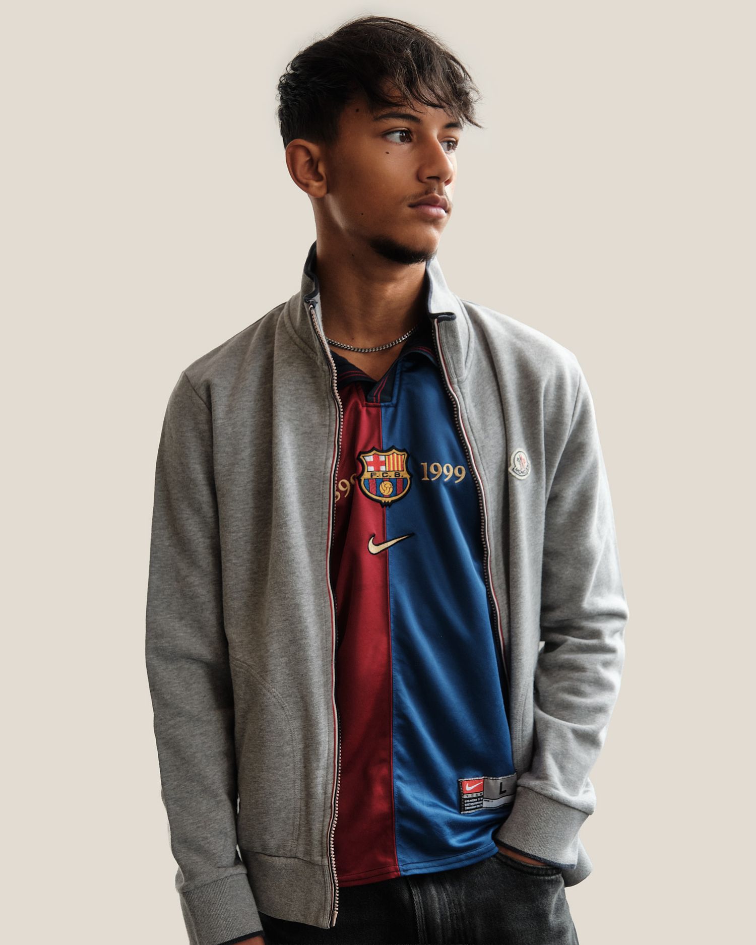 Studio fashion photo showing grey zip-up jacket with red and blue vintage sports jersey.