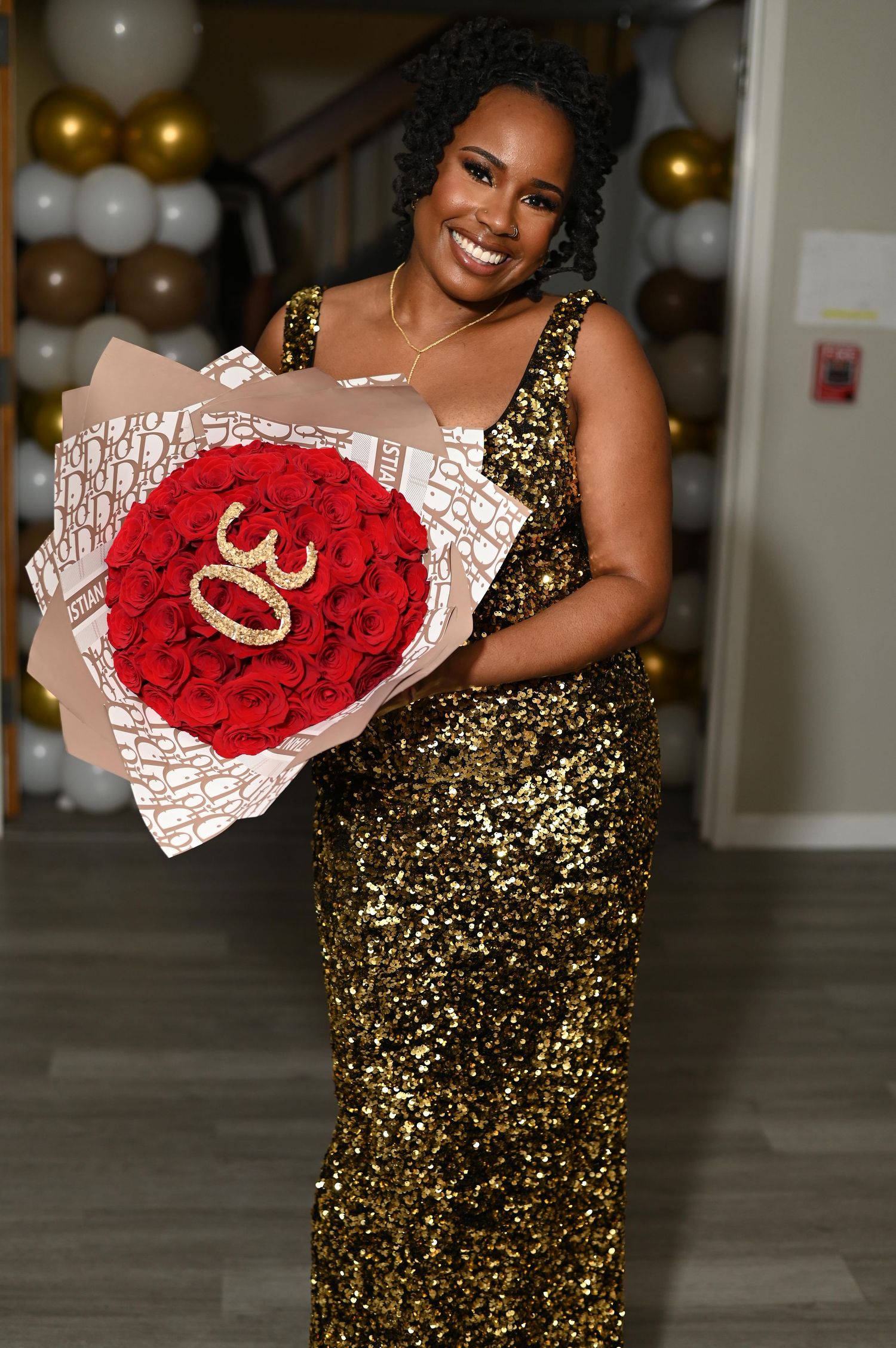 A celebratory scene with someone in a gold sequin dress holding a bouquet of red roses.