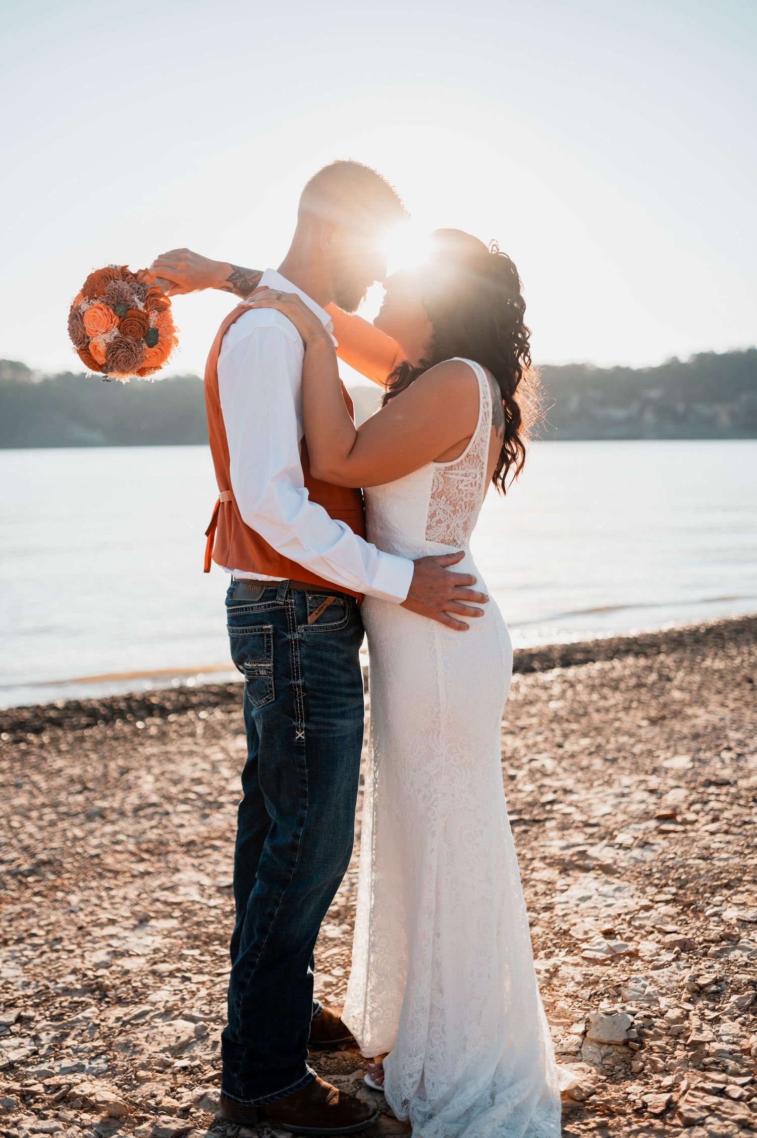 Romantic beach wedding photos at sunset with couple embracing by the water's edge.