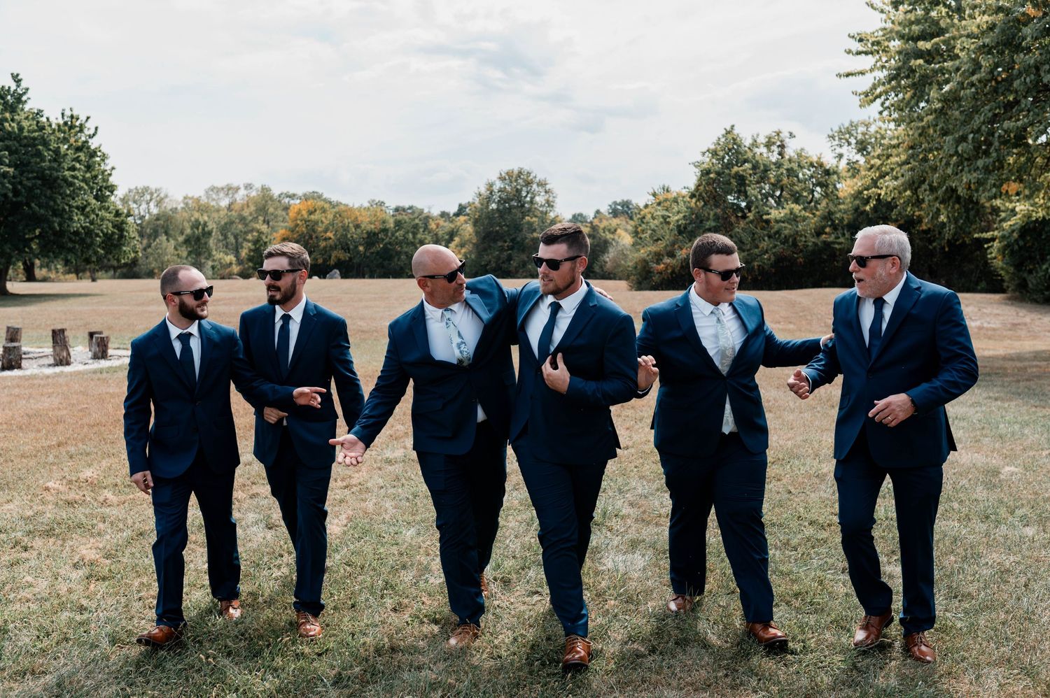 Groomsmen in navy suits lined up outdoors for casual group photo.