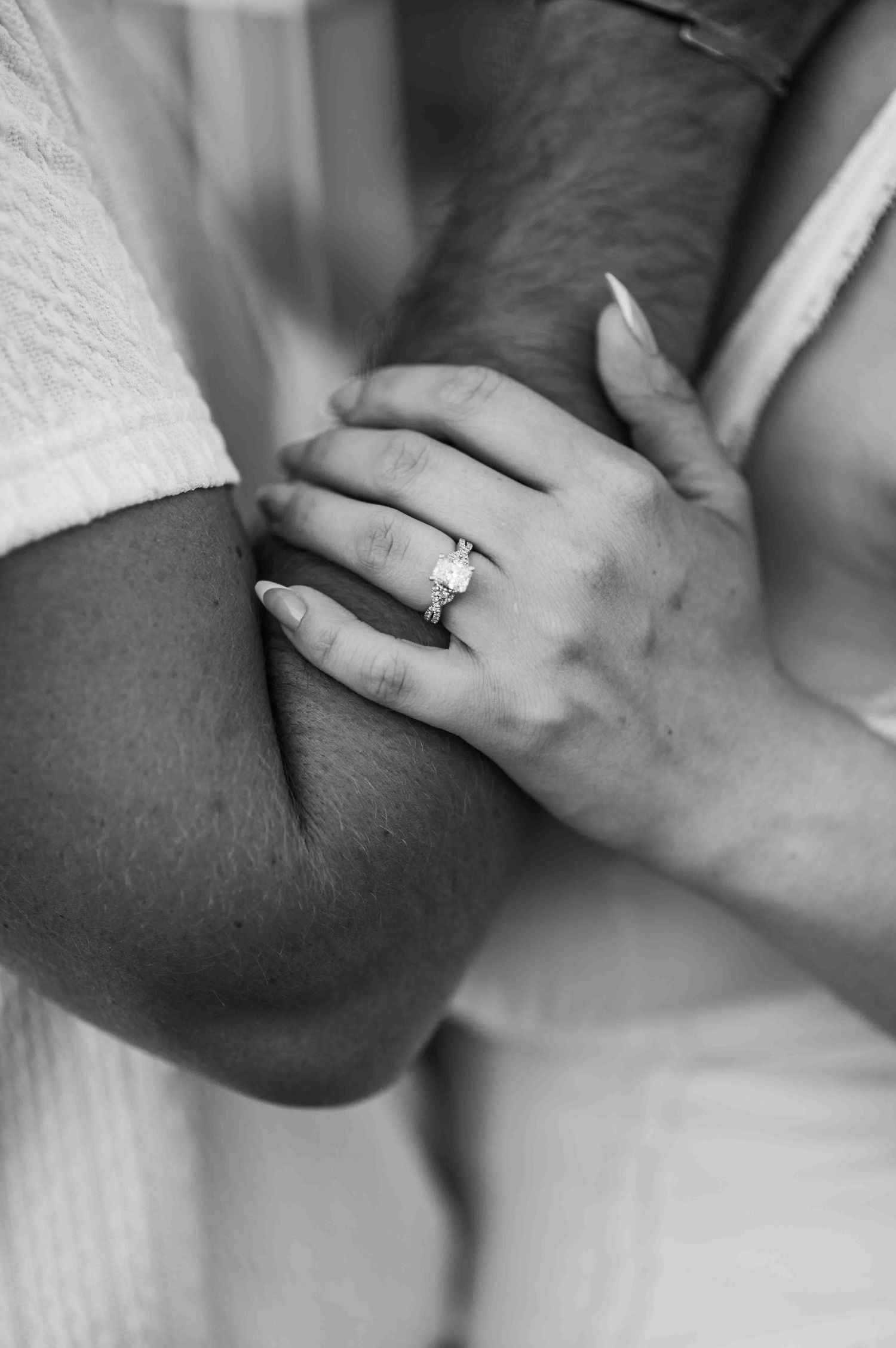 Intimate black and white detail of hands with wedding rings.