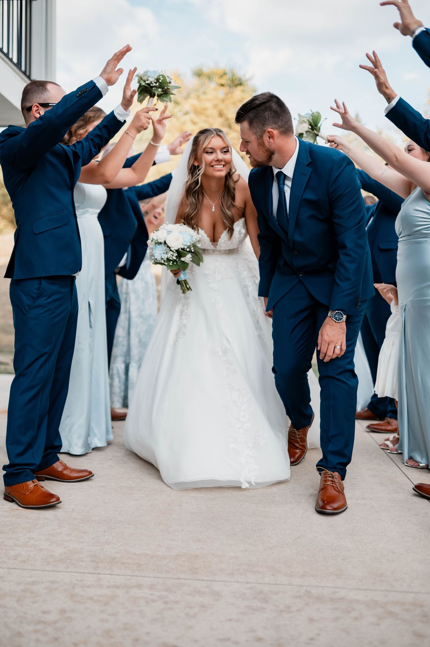 Wedding party in navy suits and light blue dresses dancing in a fun group photo sequence.