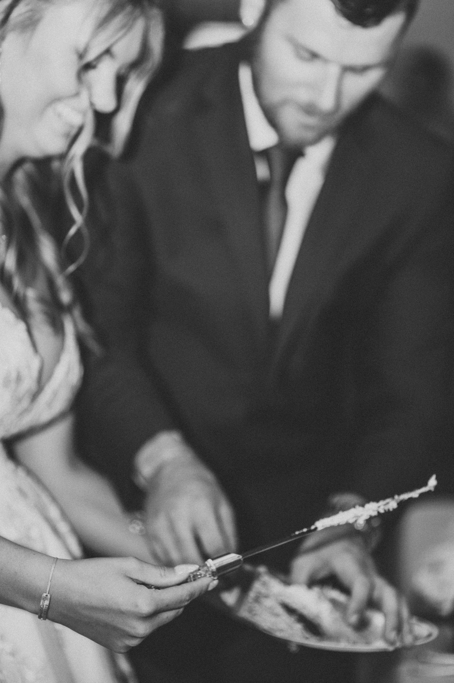 Candid black and white photo of bride and groom cutting cake.