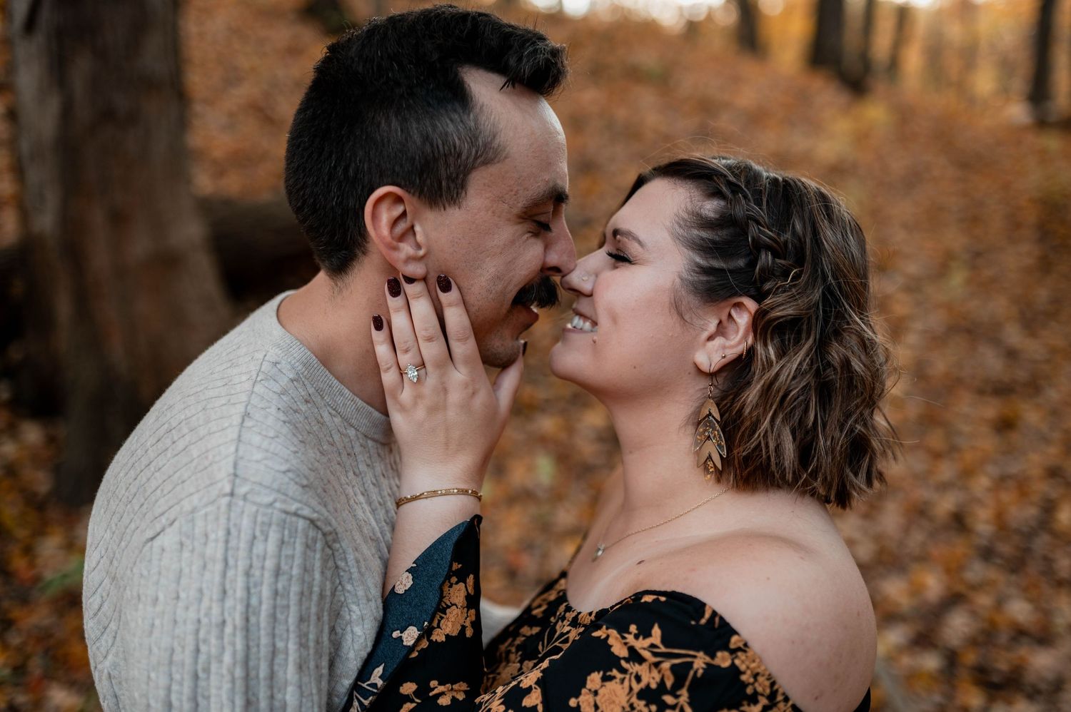 Couple embracing in autumn forest setting with fallen leaves creating a romantic atmosphere.