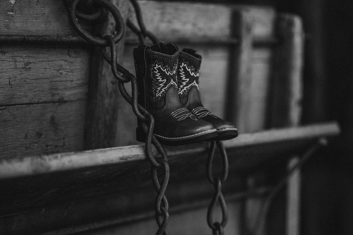 Black boots balanced on rustic wooden beams in monochrome.