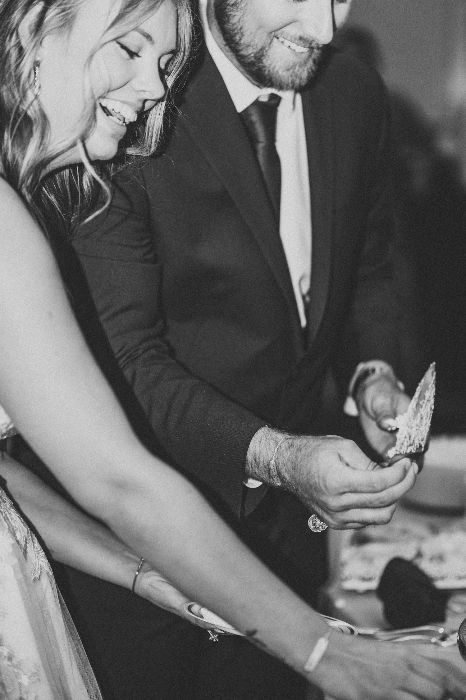 Black and white candid shot of couple sharing intimate moment during wedding reception.