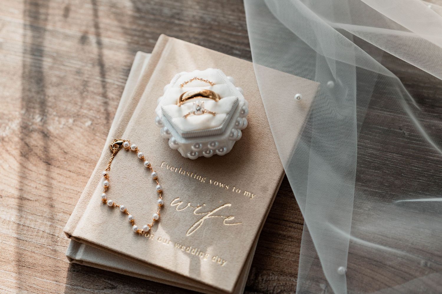 Wedding accessories and jewelry laid out on light colored fabric.