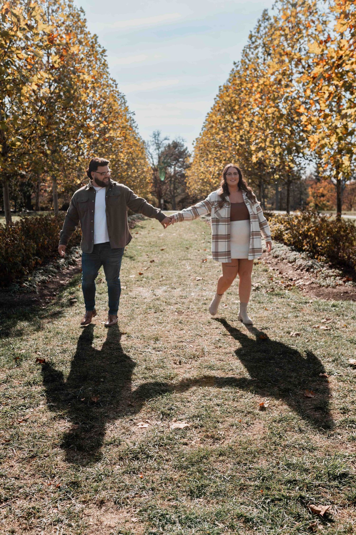 Couple dancing and playing in autumn field with golden leaves.