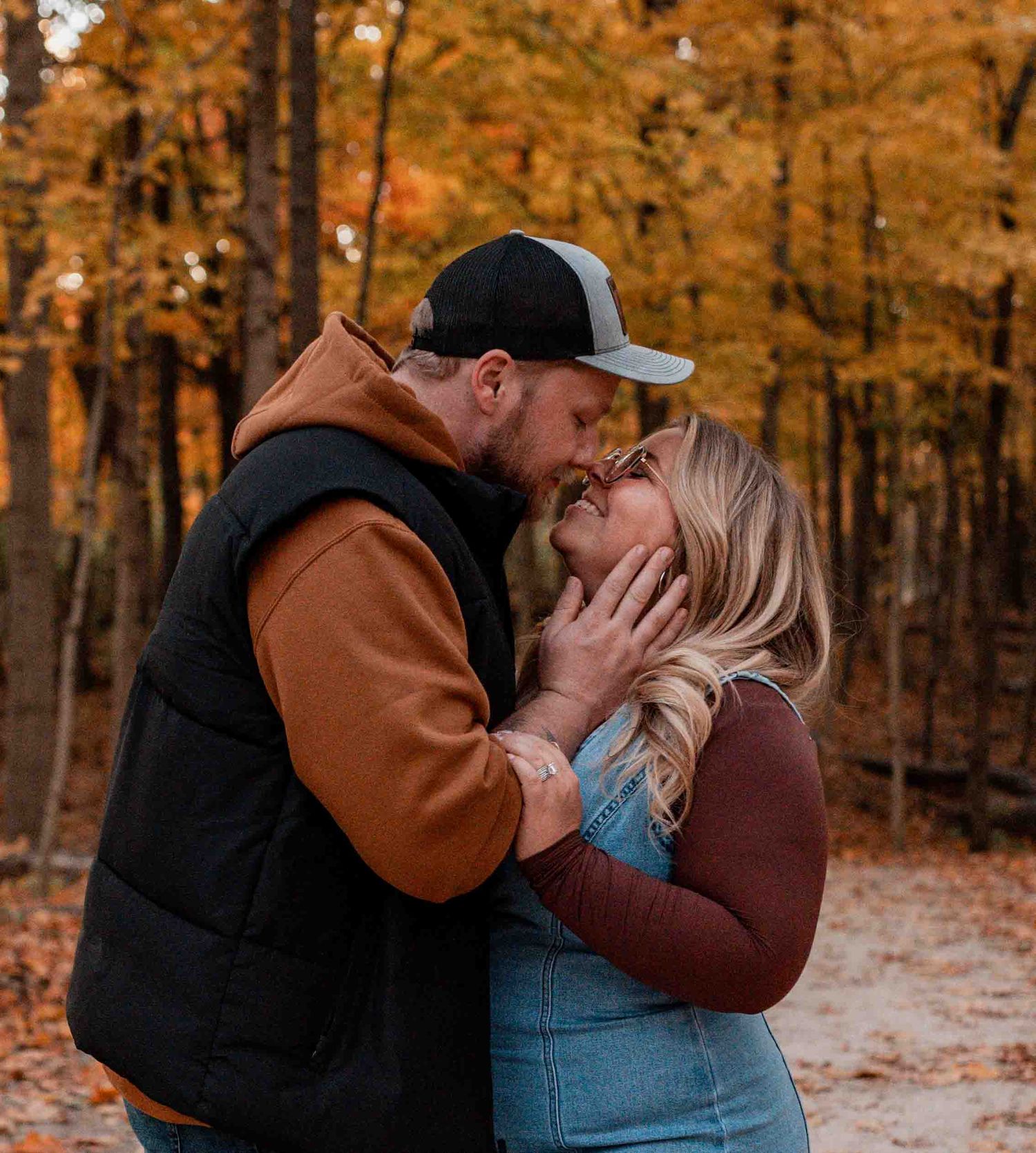 Romantic autumn engagement photos in forest with orange fall foliage.