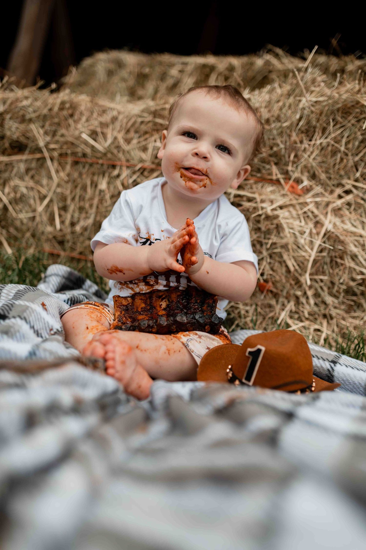 Baby sitting on blanket playing messily with ribs and fall decorations.
