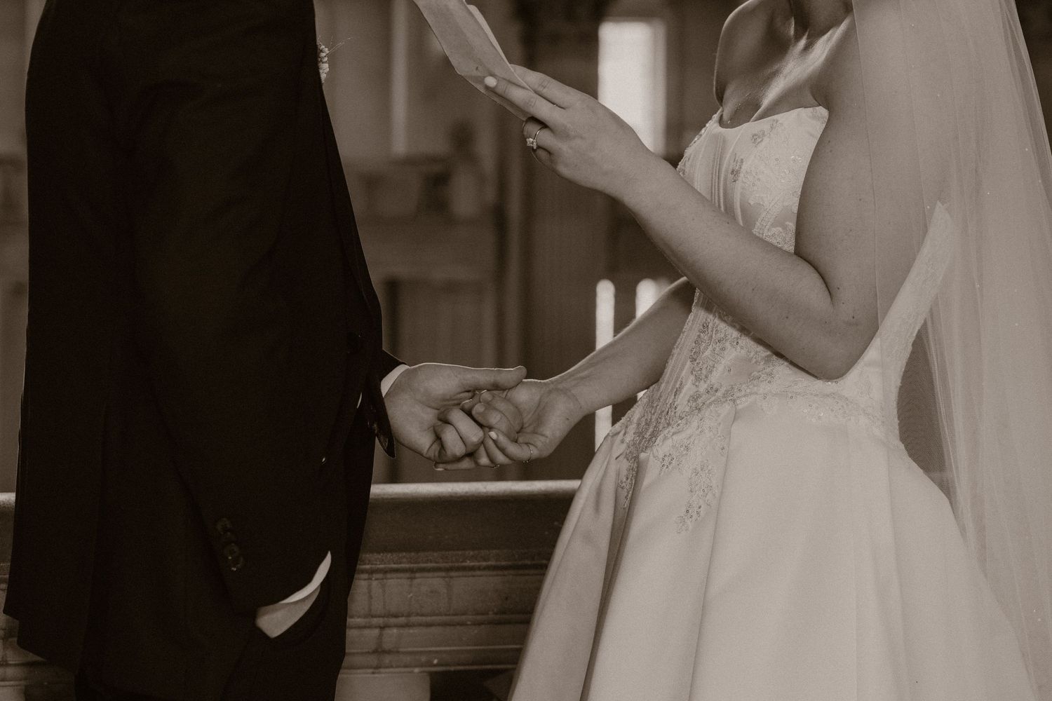 Bride and groom exchanging rings during a wedding ceremony, captured in elegant sepia tone.