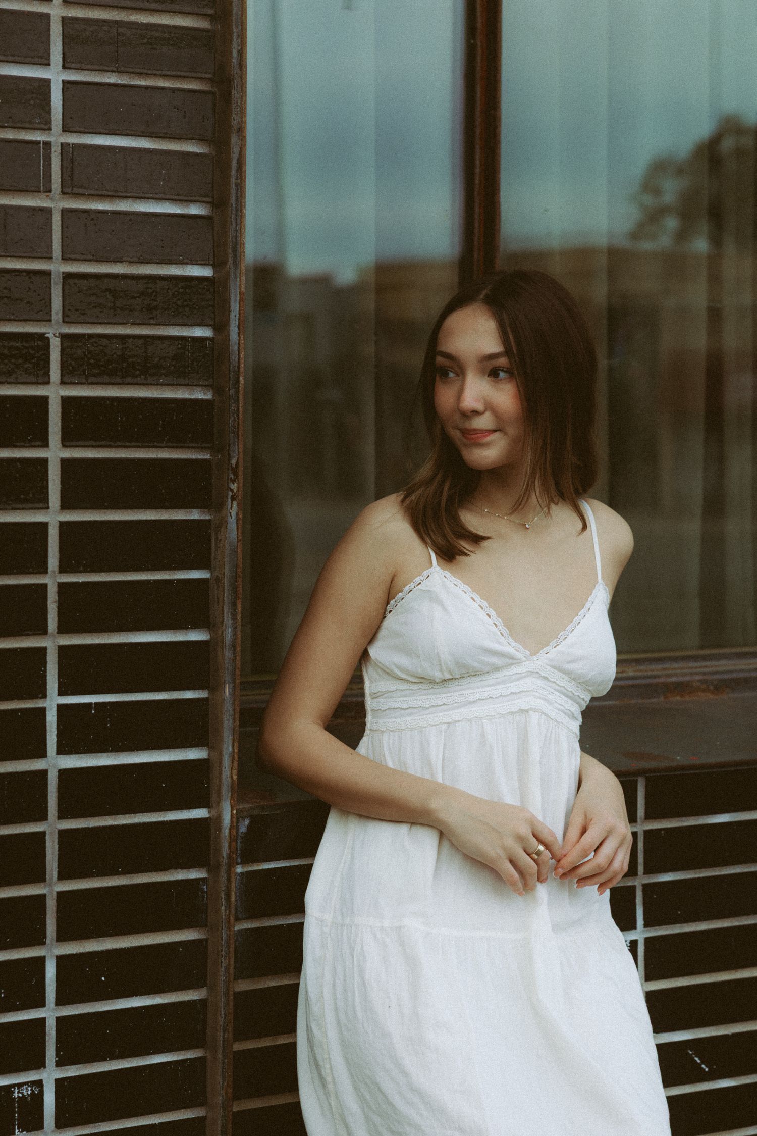 Ethereal white dress photographs against dark window blinds in an urban setting.