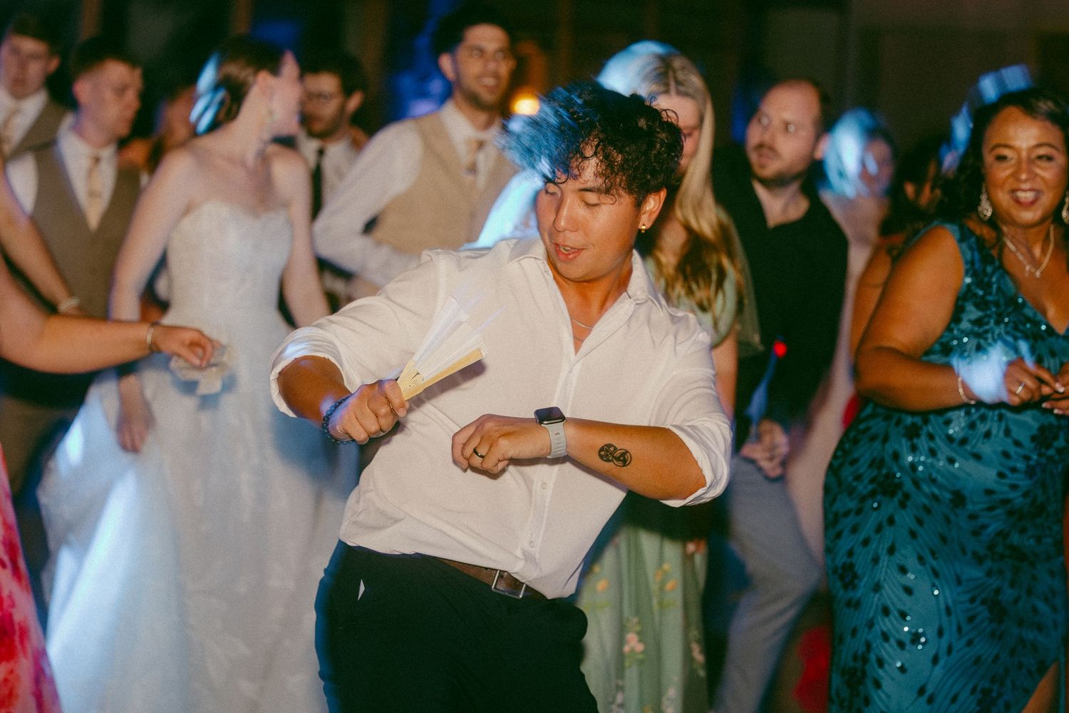Guests dancing energetically at a wedding reception, man in white shirt dancing in foreground.
