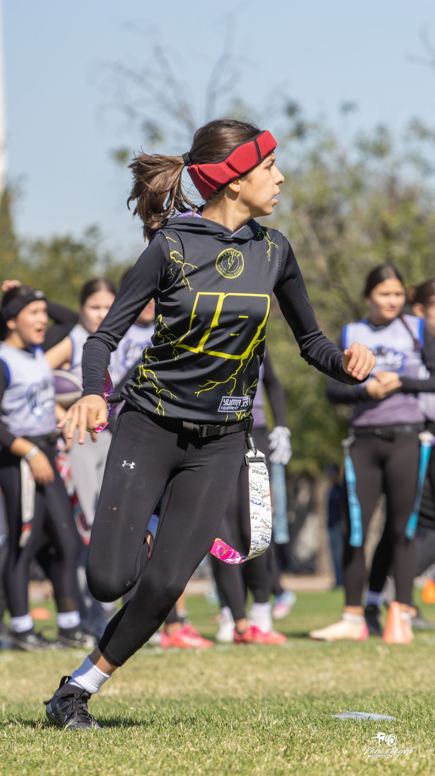 Ultimate frisbee player in black athletic wear and red headband throws disc during outdoor game.
