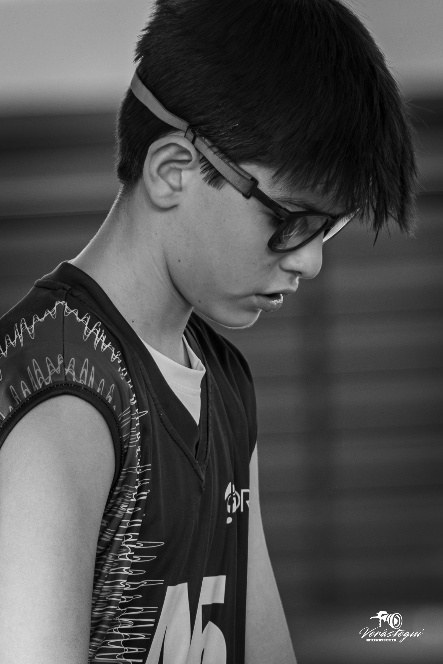 A black and white portrait of a basketball player wearing glasses and a jersey with number 15.