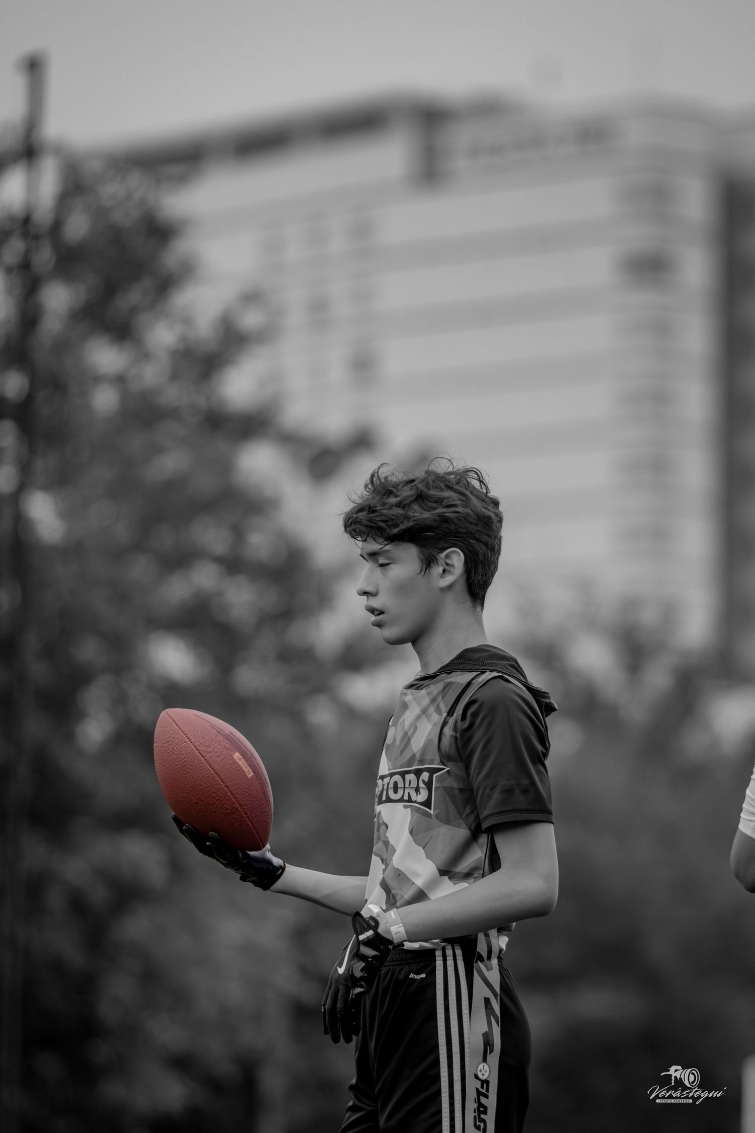 Young athlete holding a football during an outdoor game in black and white photography.