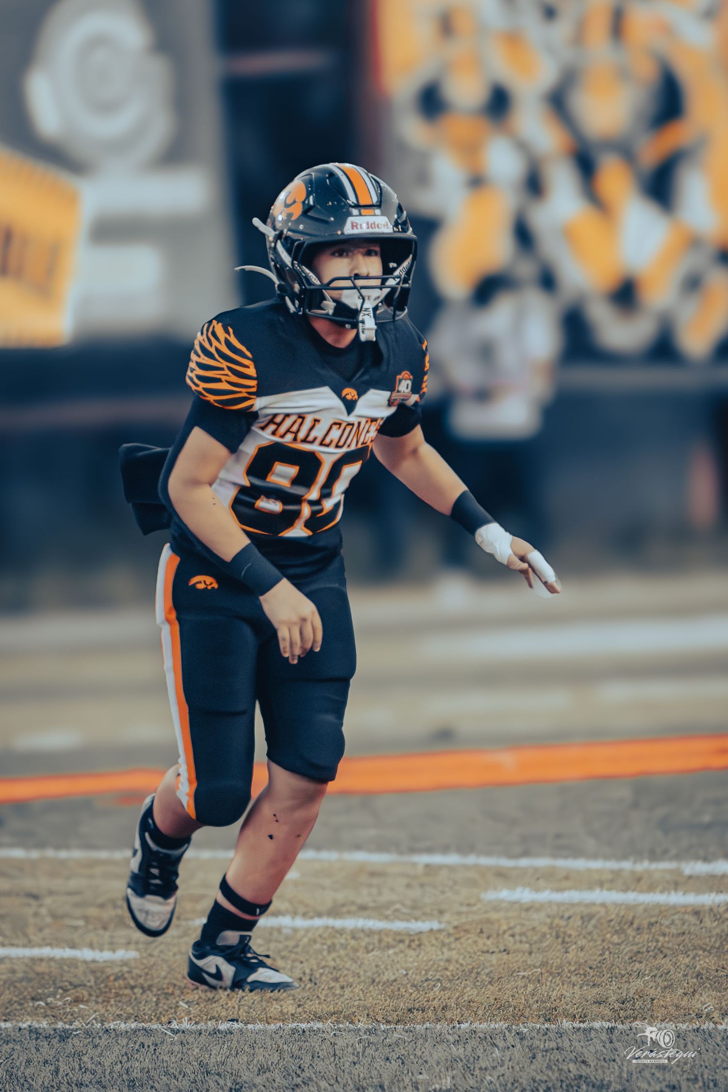 Football player in black and orange Falcons uniform, number 80, running on field during a game.