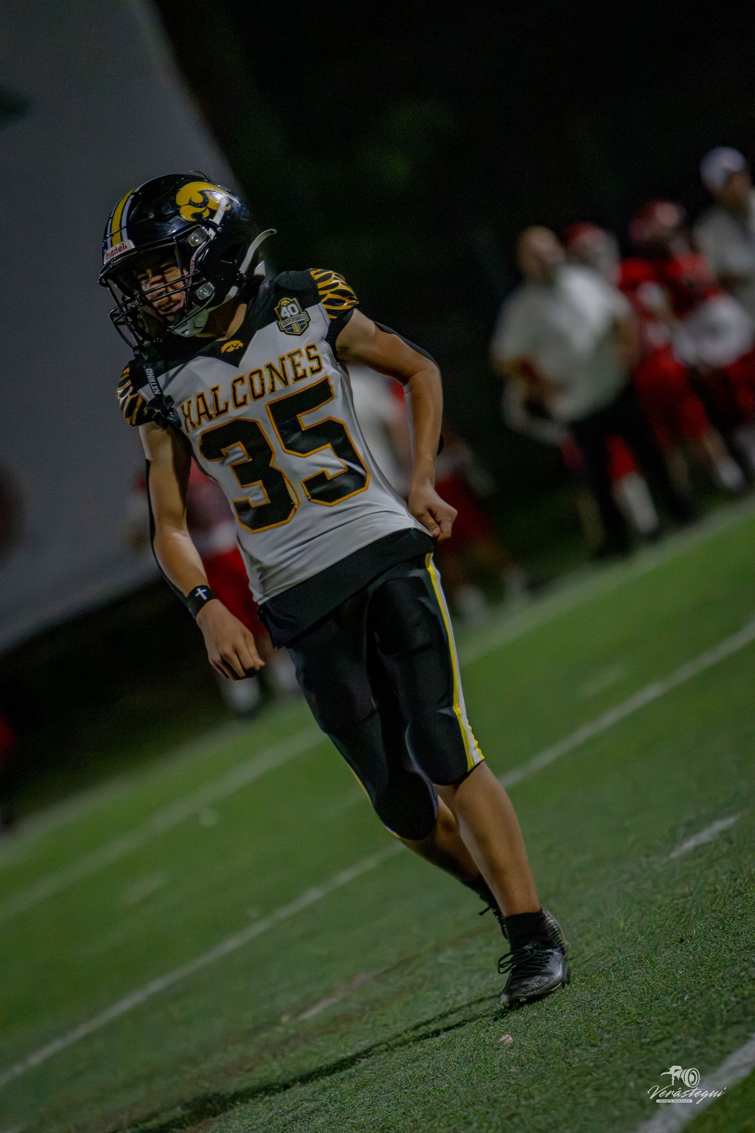 Football player #35 in Falcons uniform running on field during night game.