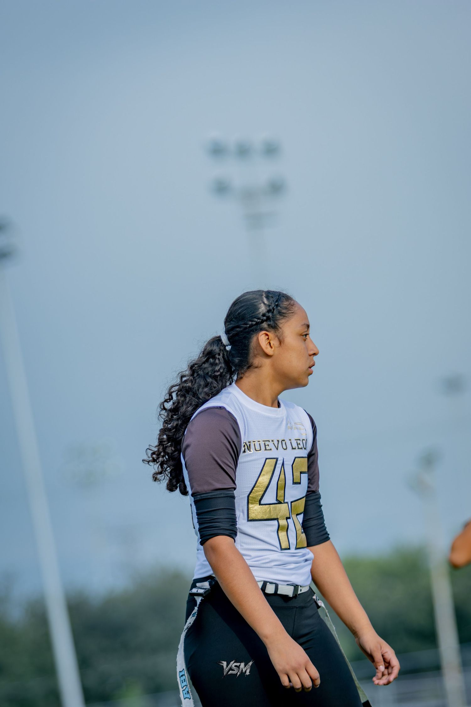 Female athlete wearing Nuevo Leon jersey number 42 stands on a sports field during a game.