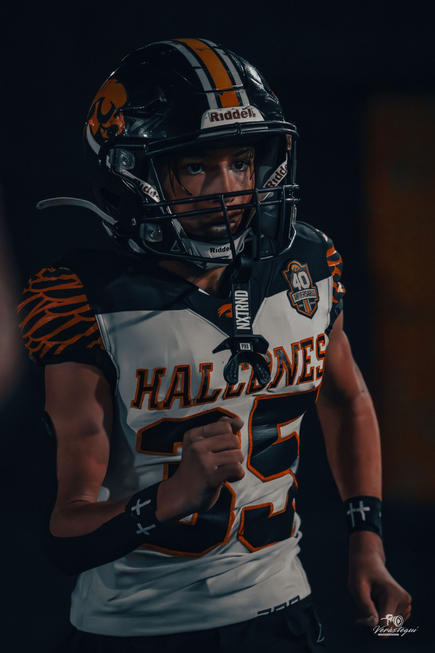 Football player in Halldanes jersey number 35 wearing Riddell helmet, poised in dramatic stadium tunnel lighting.