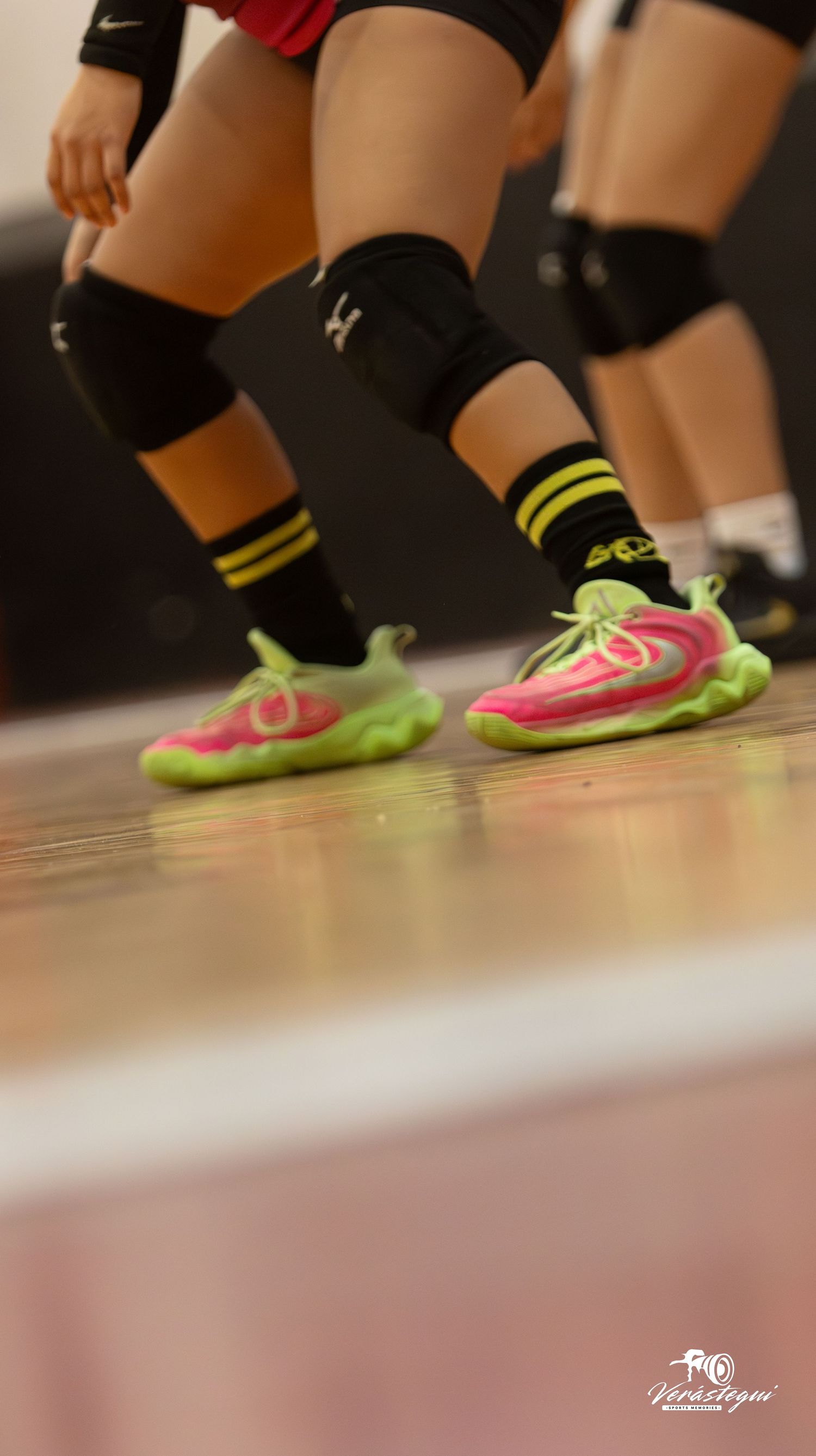 Motion blur sequence of pink and neon yellow athletic shoes on a wooden floor during indoor sports activity.