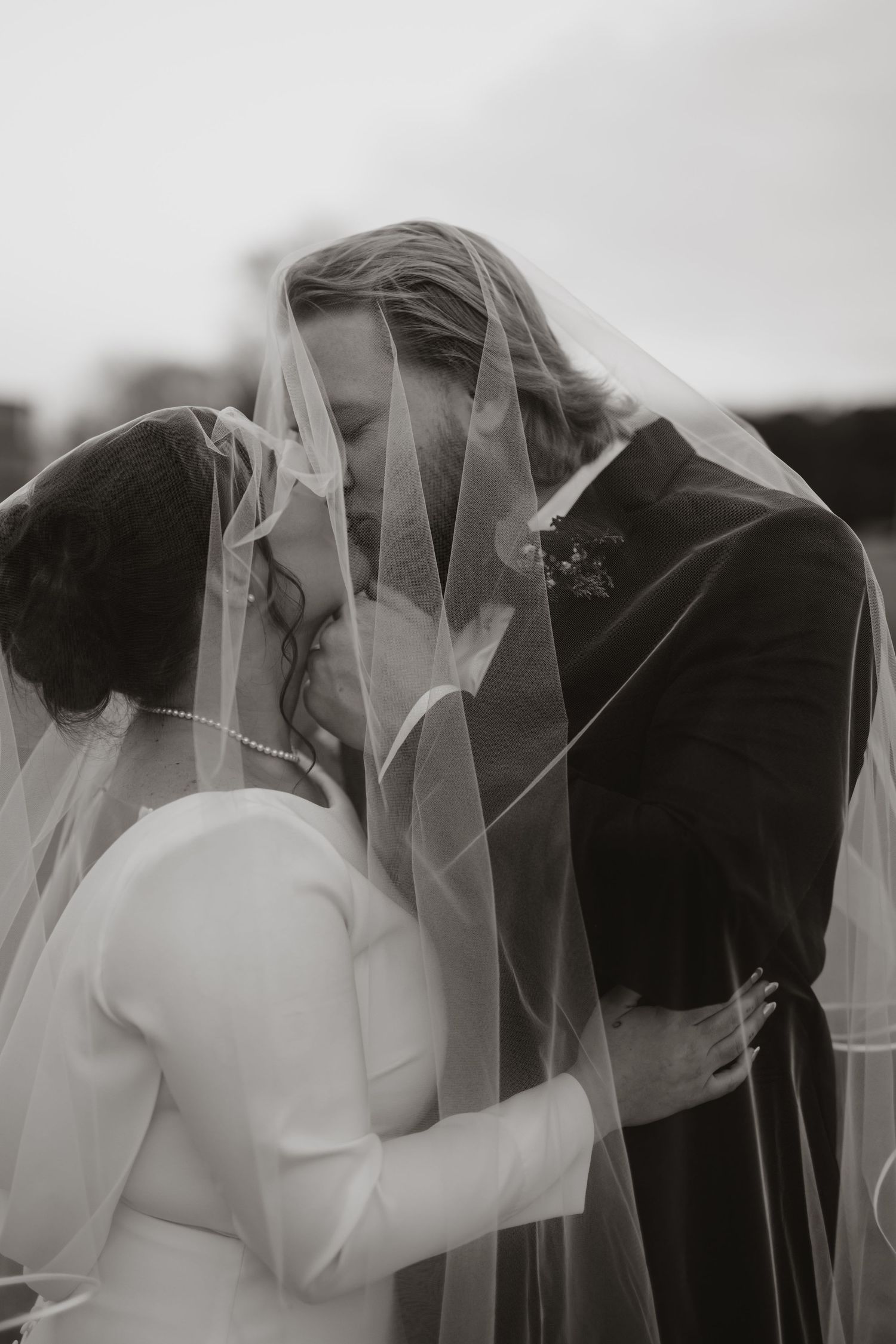 a black and white portrait of a couple kissing under the brides veil in Alabama