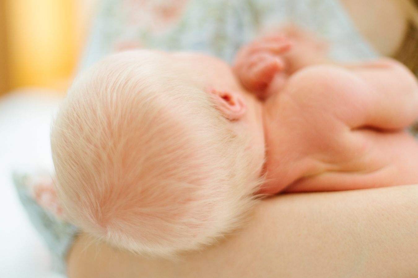 Suloisen vastasyntyneen vaaleat hiukset, yksityiskohta rennosta ja lempeästä newborn-kotikuvauksesta Lohjalla.